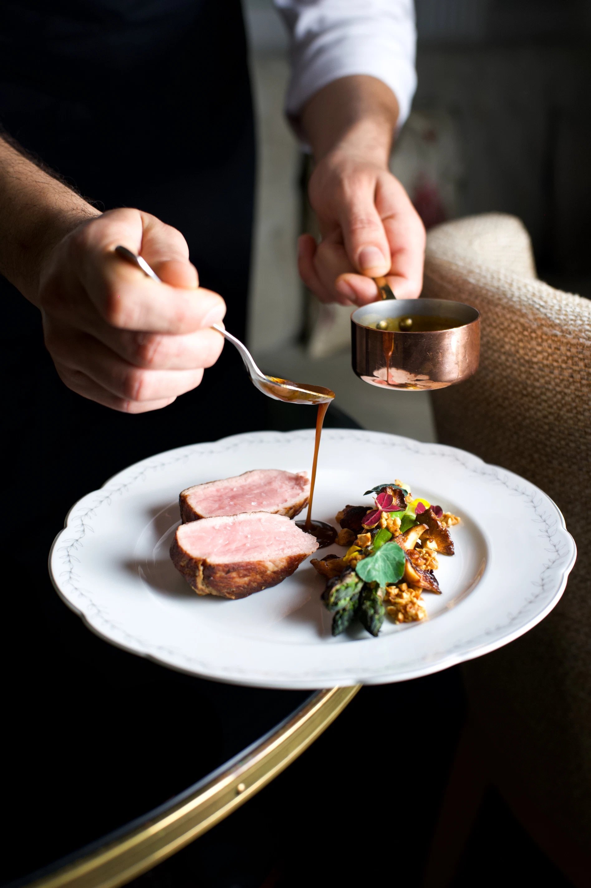 Dressage raffiné d’un plat de viande à l’Hôtel San Régis par un serveur, avec sauce versée minutieusement
