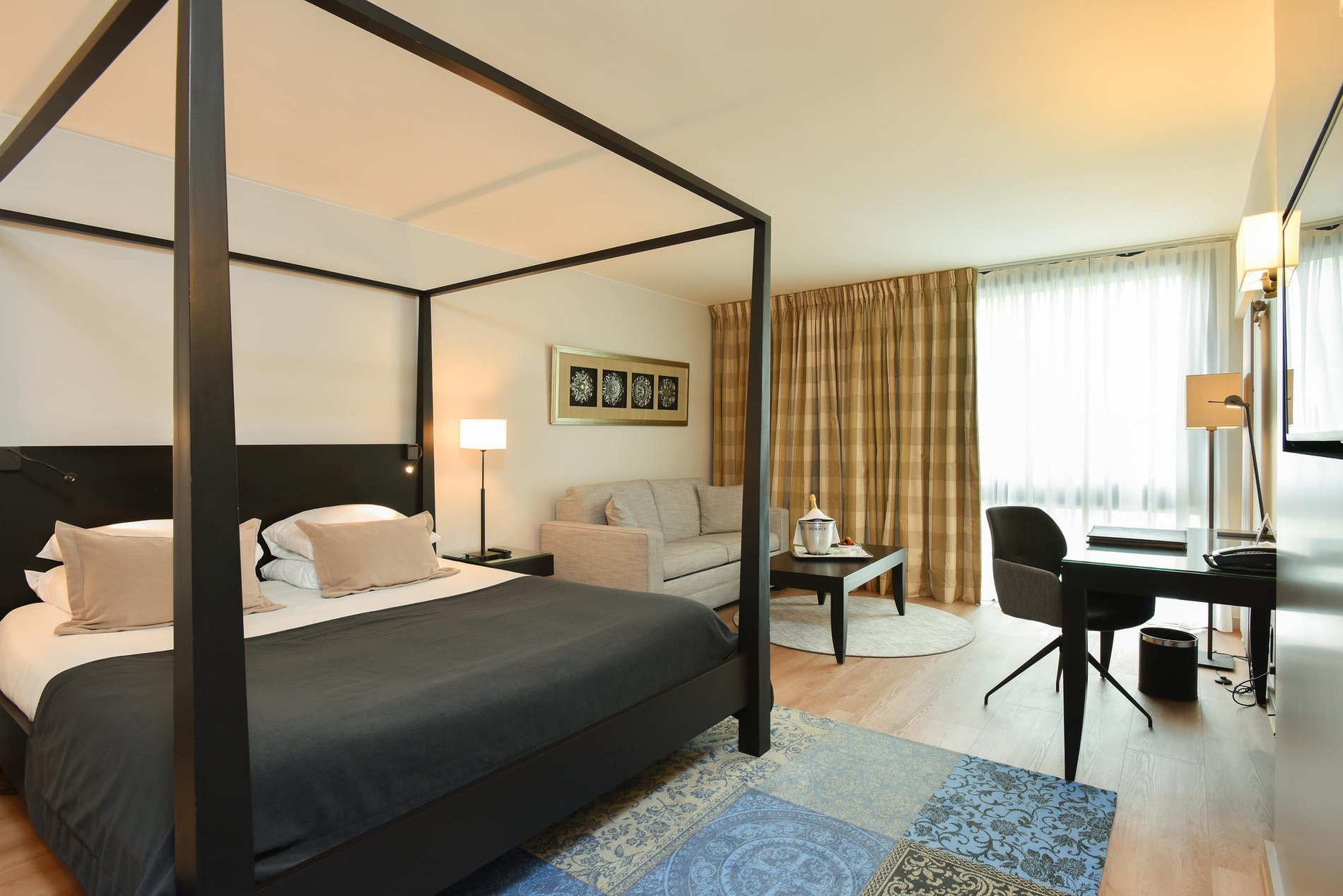 Bright room with a four-poster bed, sitting area, and large windows at Martin's Château du Lac.