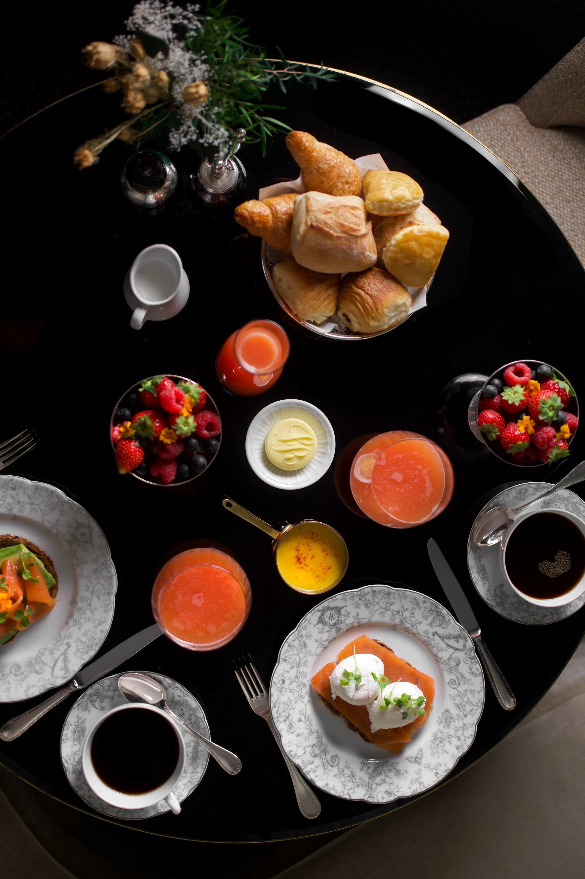 Petit-déjeuner complet à l’Hôtel San Régis Paris avec jus frais, viennoiseries, fruits et vaisselle élégante.