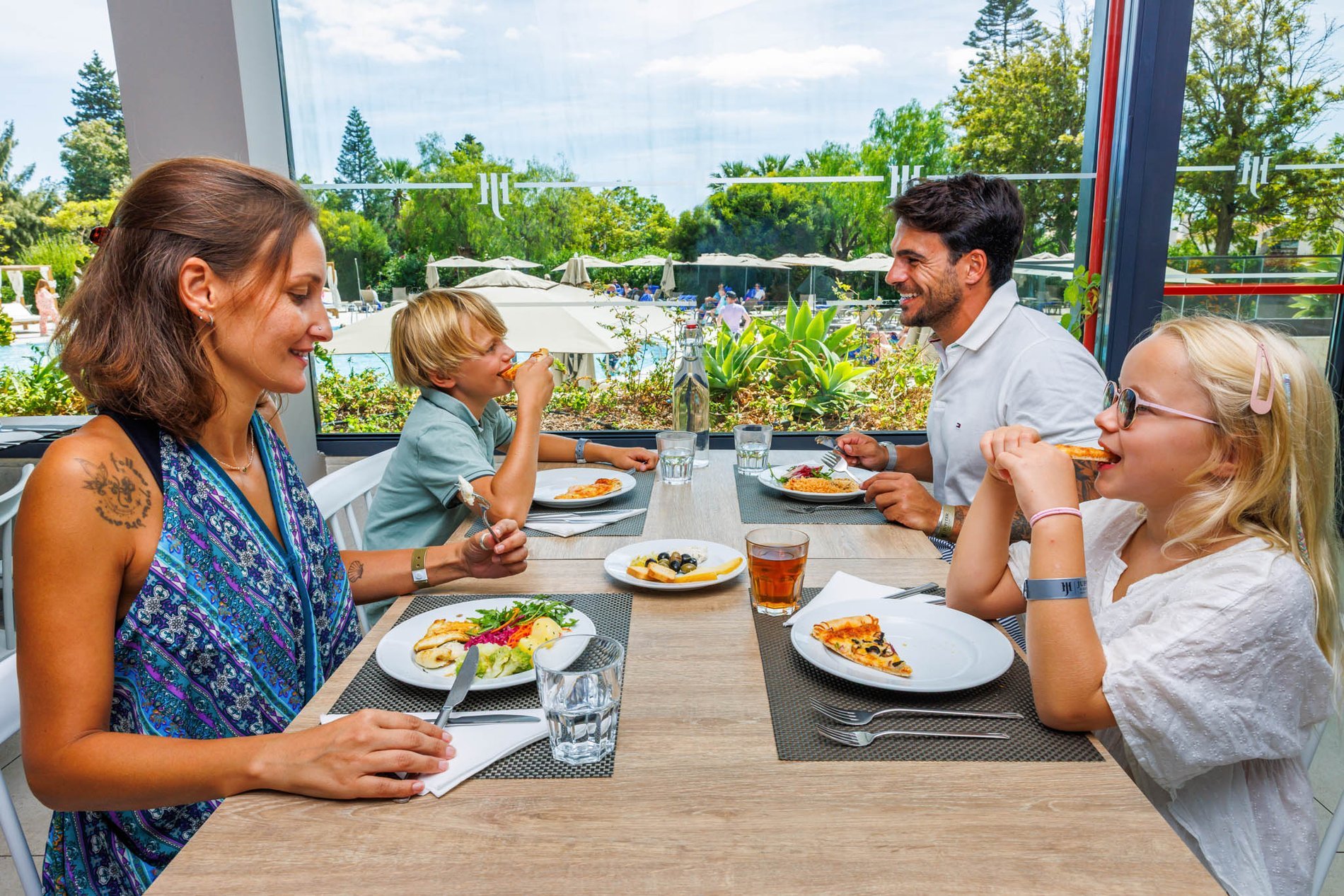 Famille partageant un moment convivial en déjeunant de la pizza au restaurant Al Italiu de l’Hôtel Jupiter Albufeira