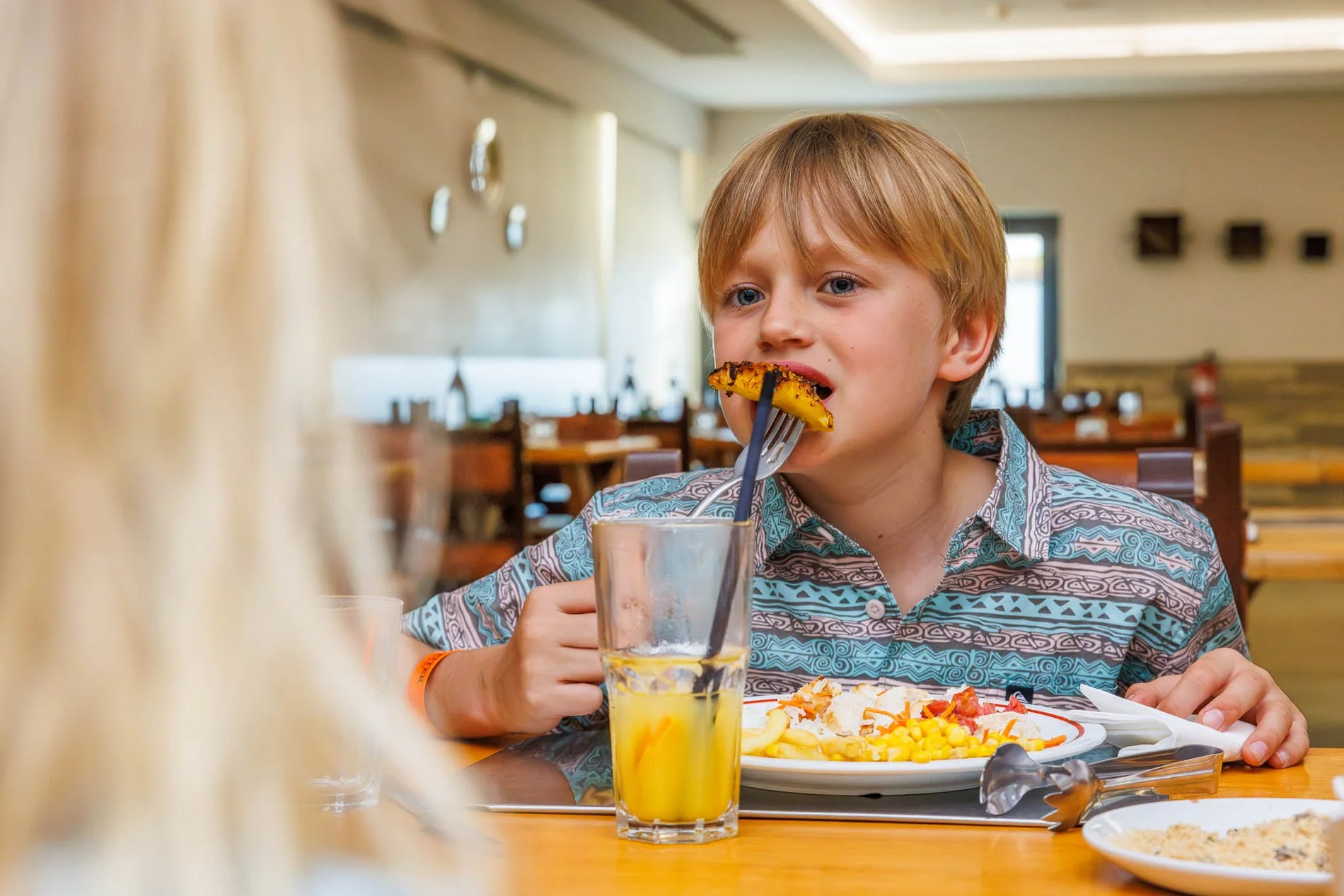 Garçon mangeant de l’ananas grillé au restaurant Taberna avec des plats typiquement brésiliens de l’Hôtel Jupiter Albufeira