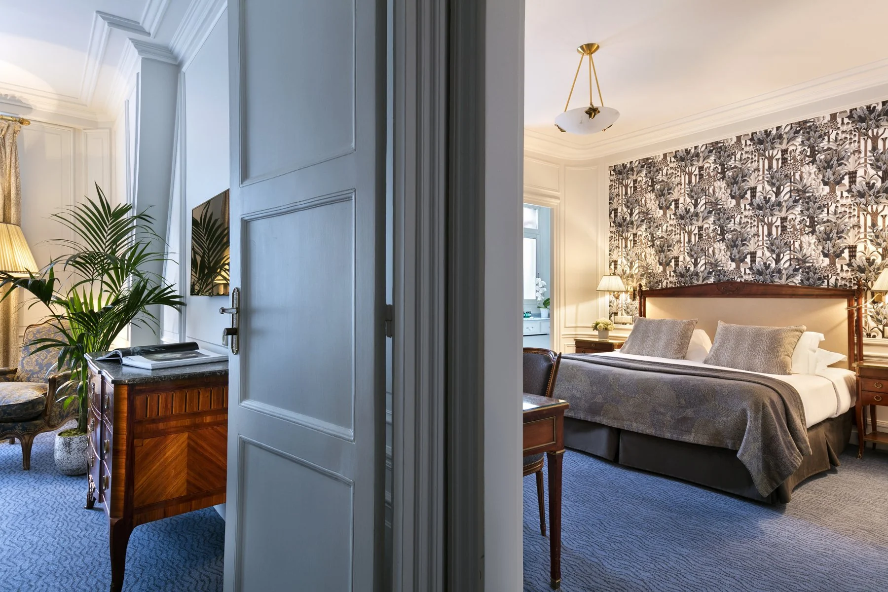 Suite de l’Hôtel San Régis avec lit double, tête de lit en bois et salon attenant dans un style classique.
