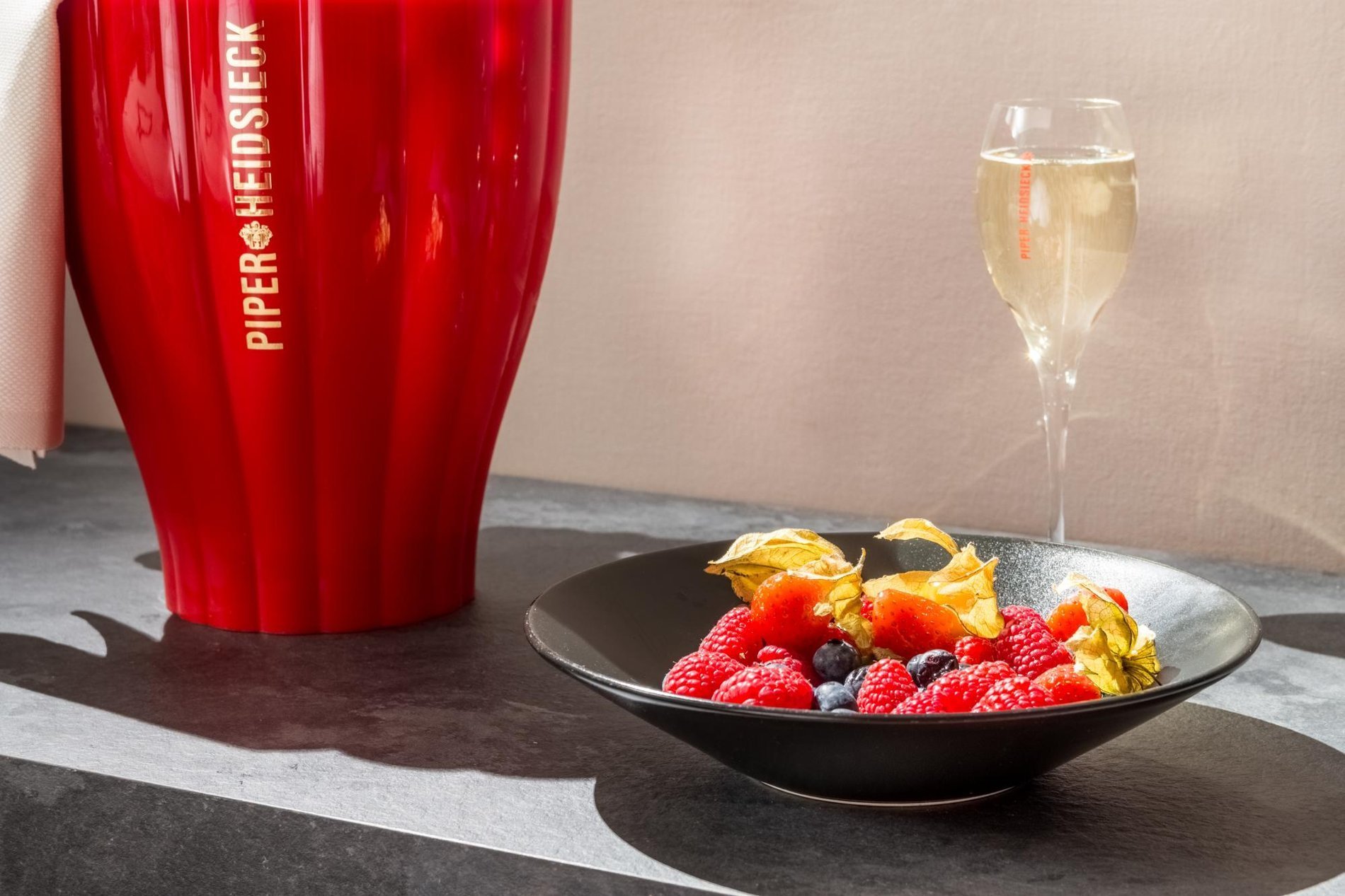 Fresh fruits with champagne beside a decorative red vase