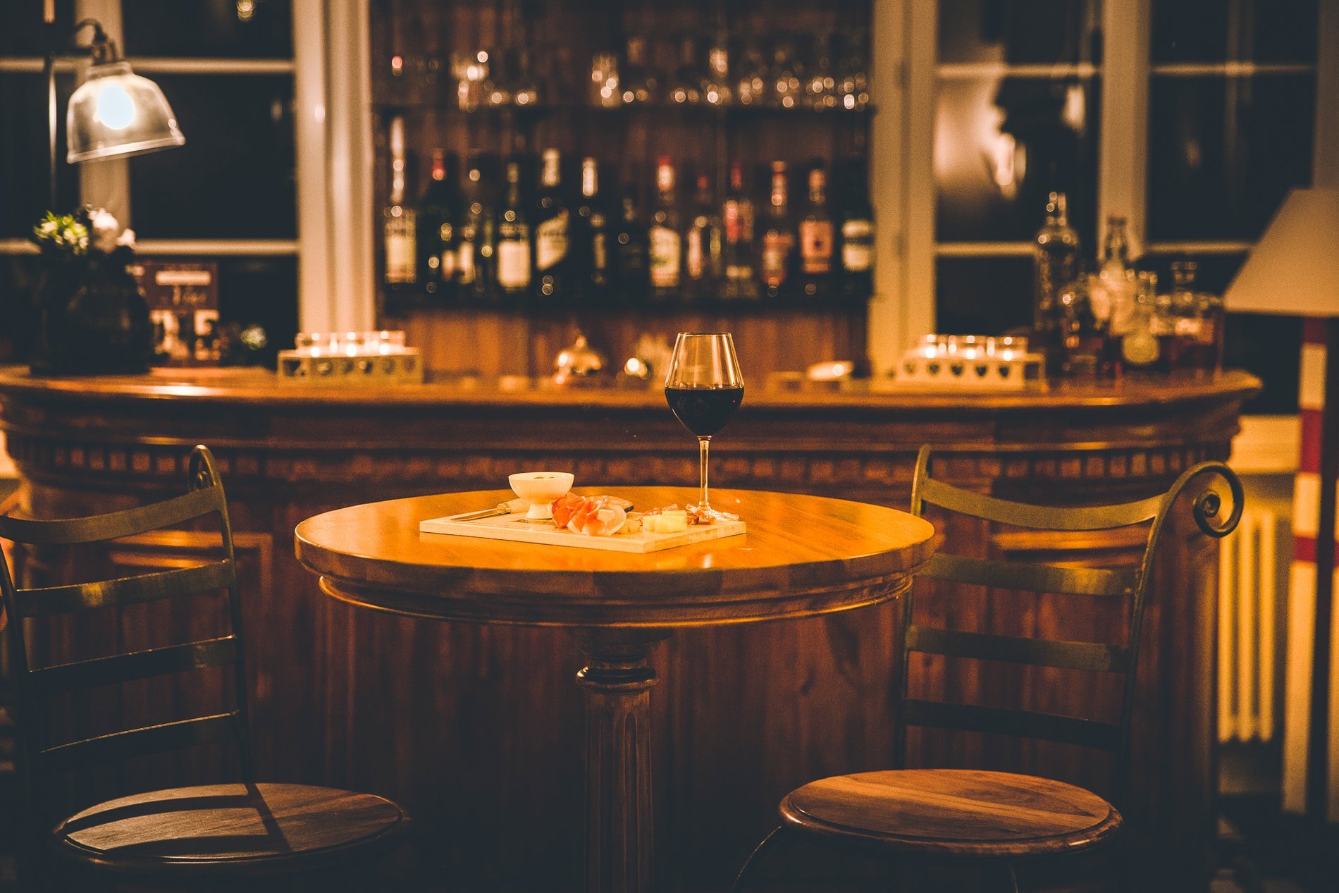 Comptoir de bar éclairé dans l'obscurité à l'Hôtel La Ramade, symbolisant l'ambiance intime du soir.