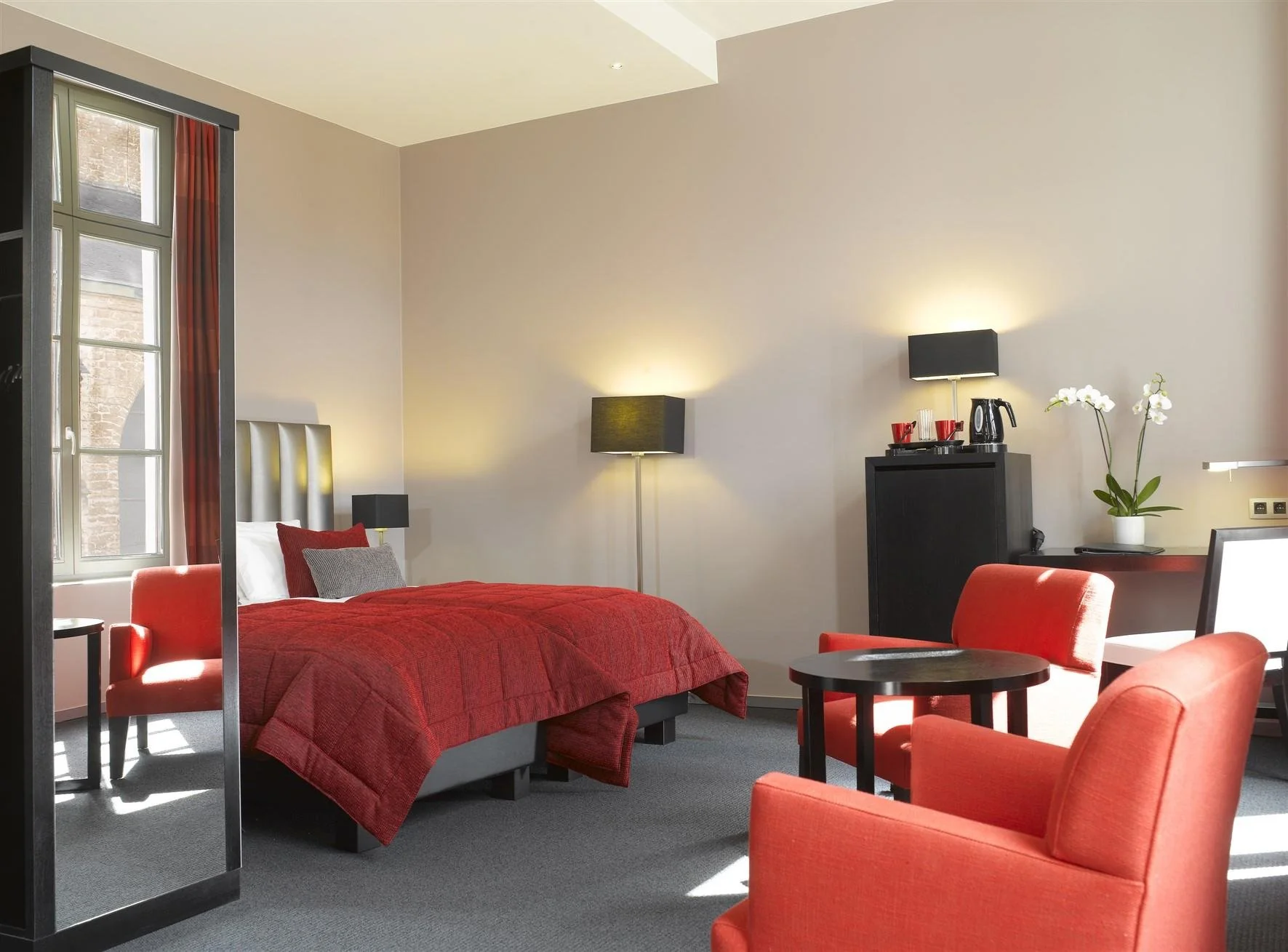 Chambre spacieuse avec fauteuils rouges au Martin's Klooster à Louvain.