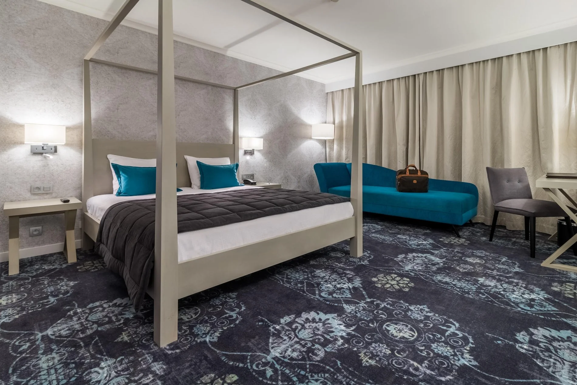 Chambre spacieuse avec lit à baldaquin blanc et coin salon bleu au Martin's Château du Lac.