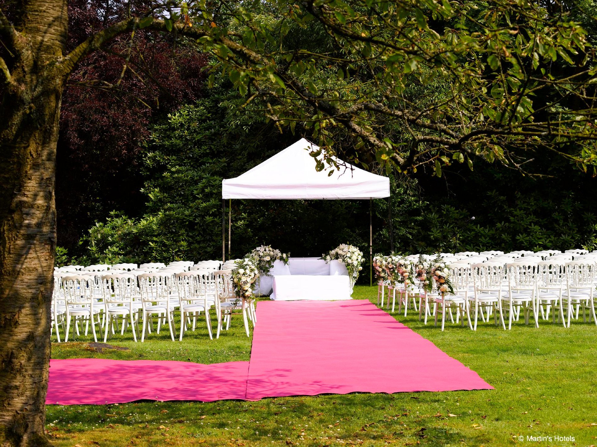 Outdoor-Hochzeitszeremonie mit rosa Gang im Martin's Manoir.
