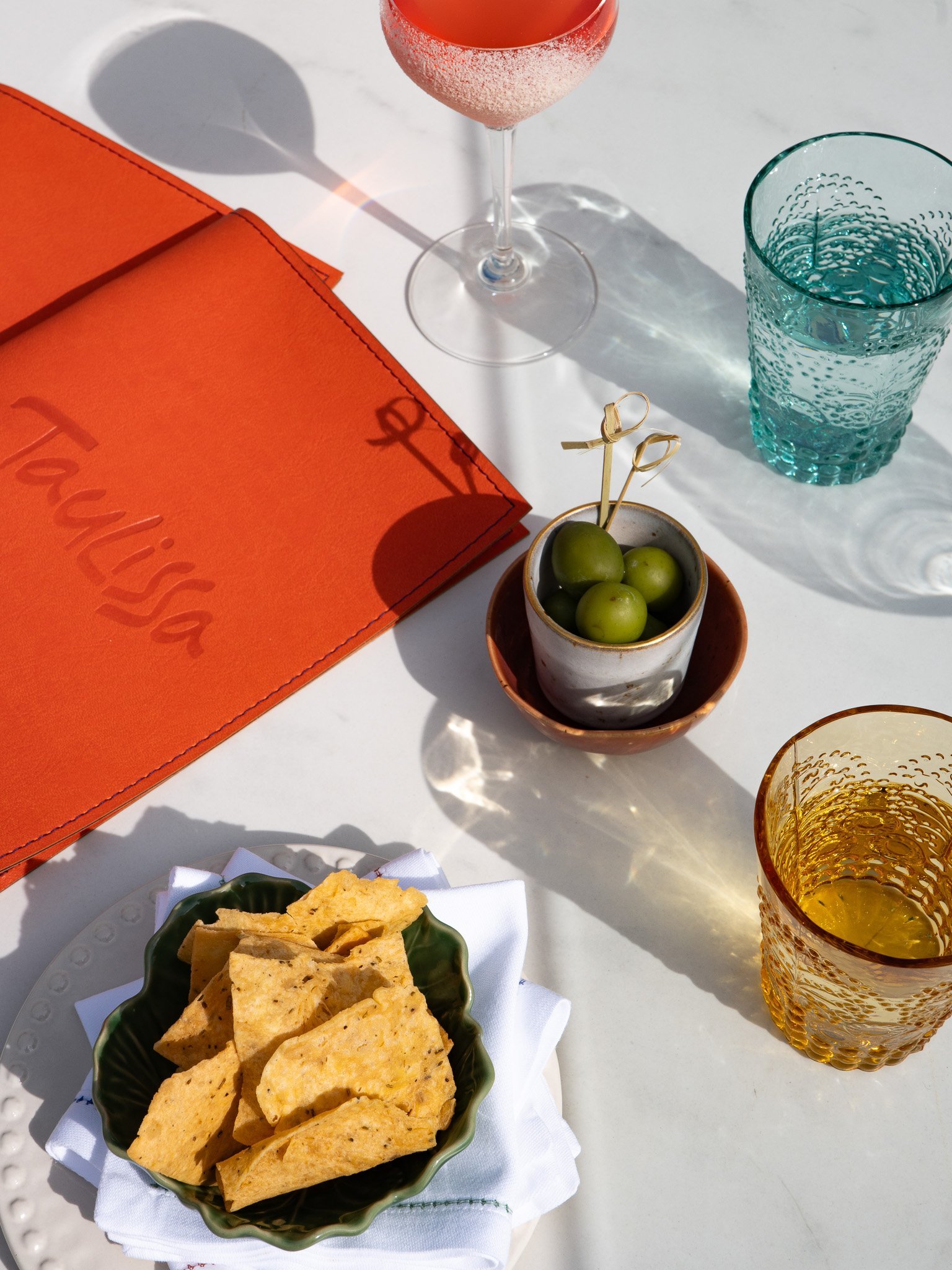 Aperitif atmosphere: glass, olives, chips, Taulissa menu.