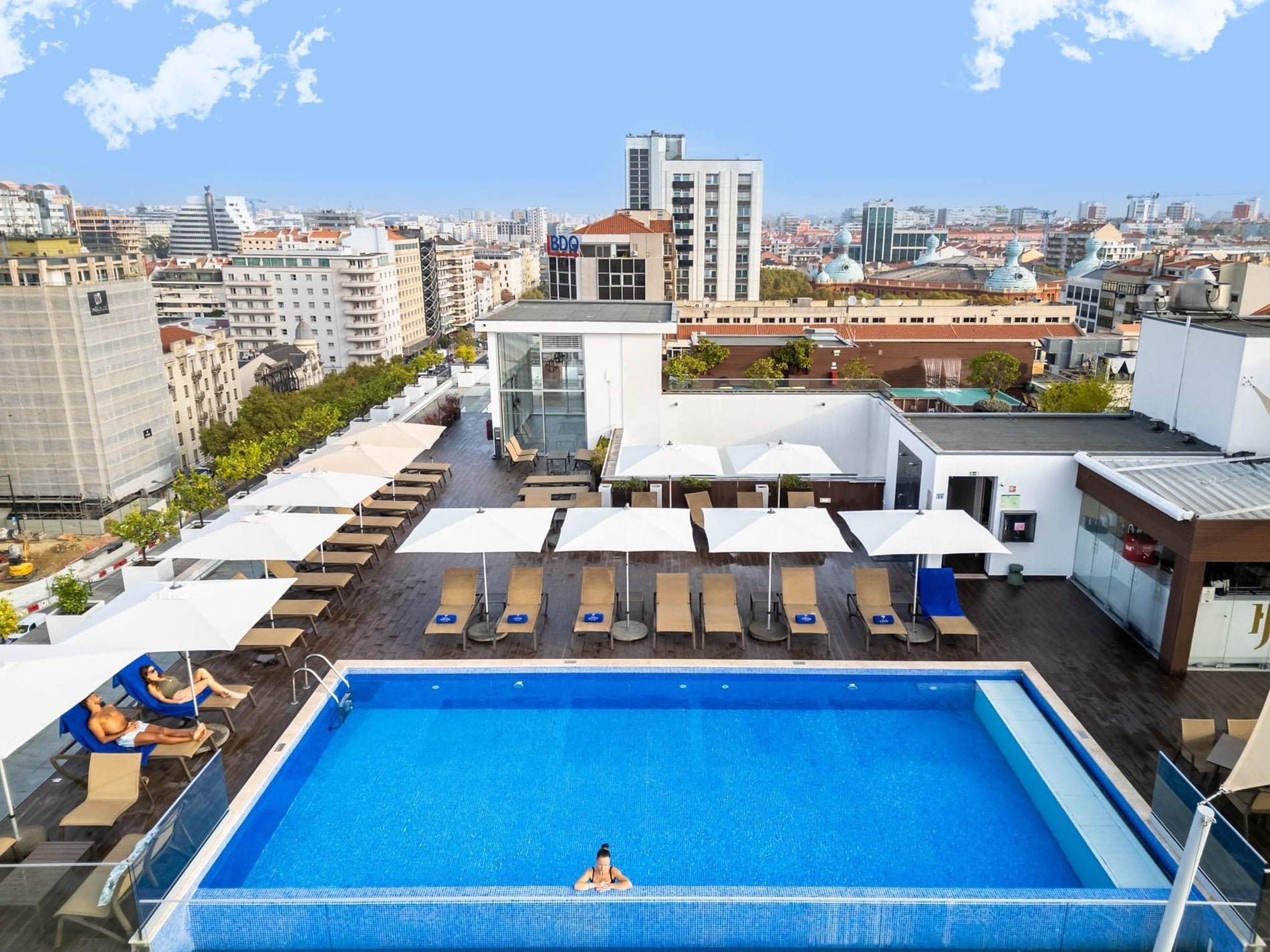 Giovane che si gode la piscina con vista sul rooftop del Jupiter Lisboa Hotel