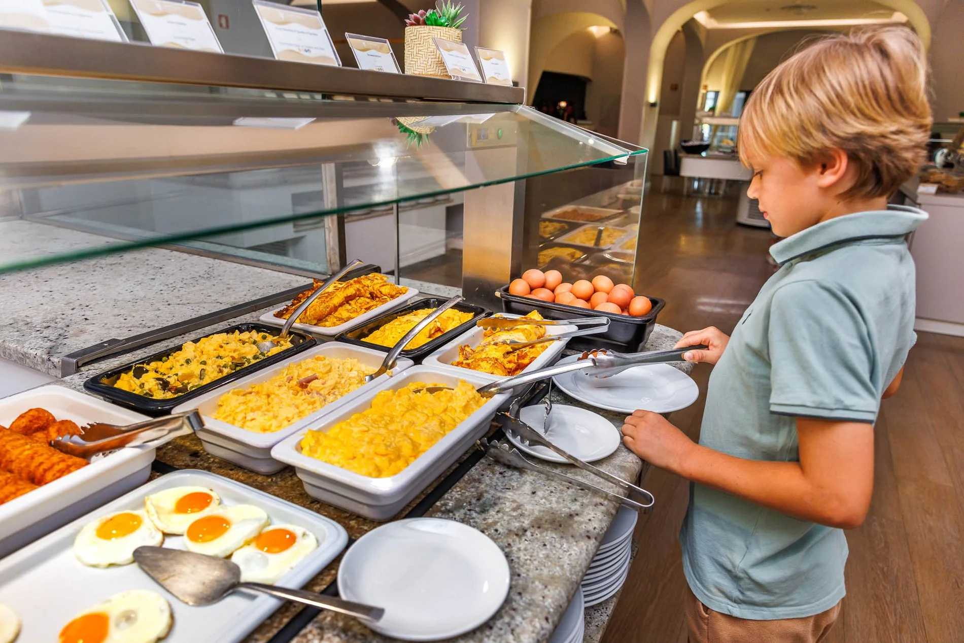 Enfant se servant au buffet du petit-déjeuner de l’Hôtel Jupiter Albufeira