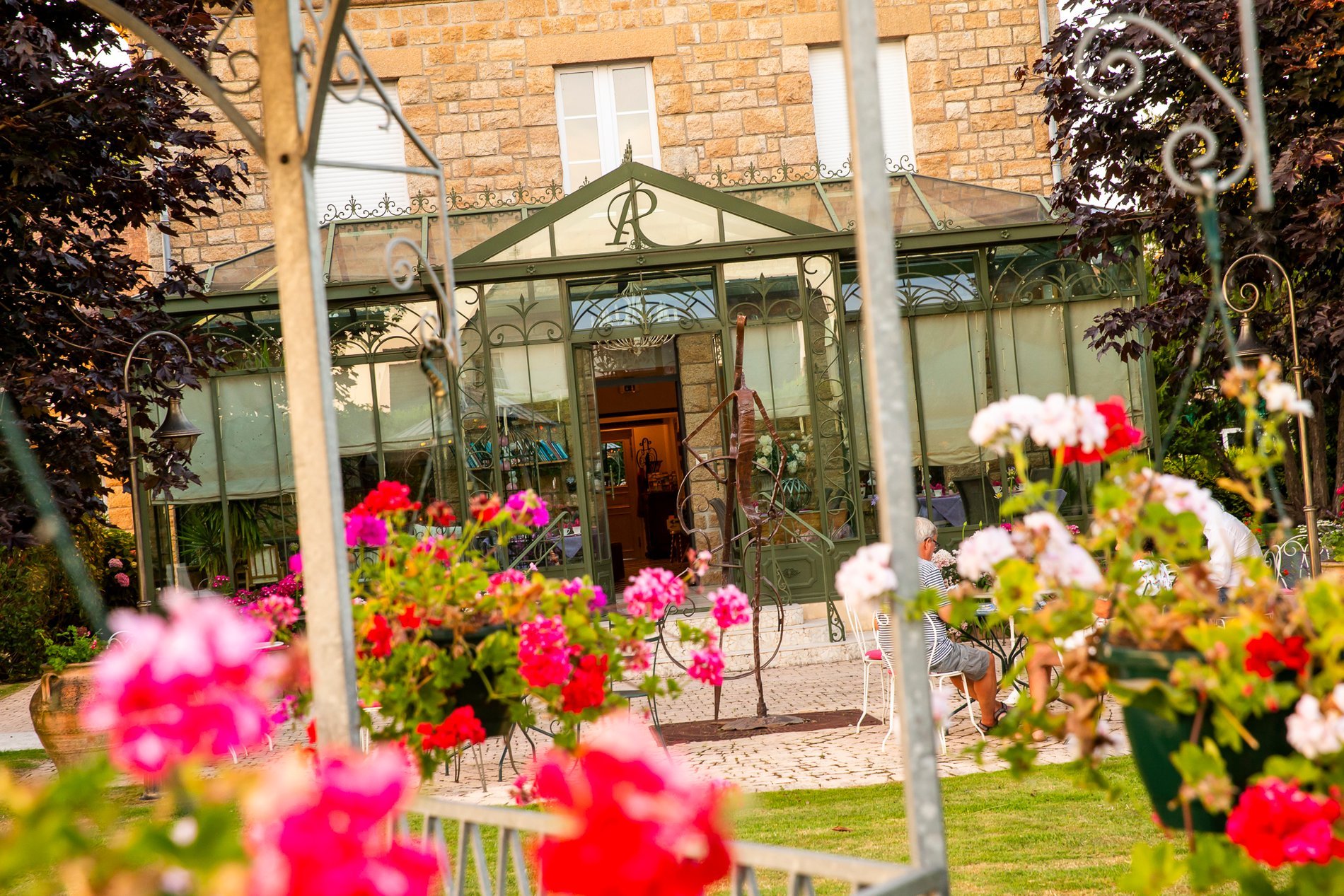 Facade of Hotel La Ramade's conservatory adorned with flowers, symbolizing a bright and welcoming space connected to nature.