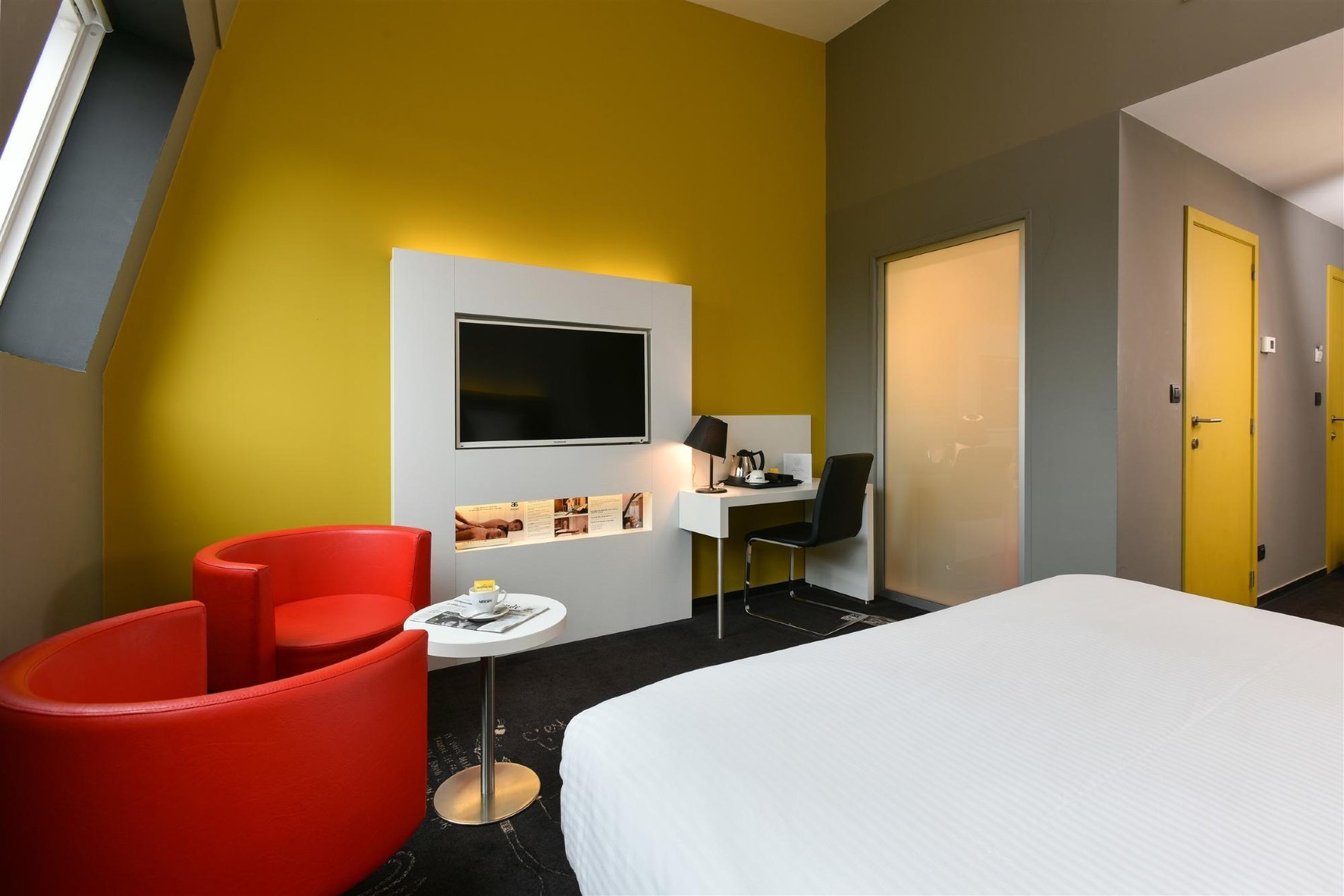 Gemütliches Plus-Zimmer mit Wandfernseher und gelber Dekoration.