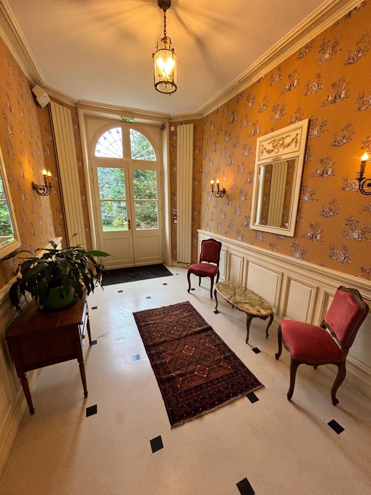 Château de la Rozelle, Hall d'entrée élégant avec des chaises anciennes et un tapis, à La Rochelle.