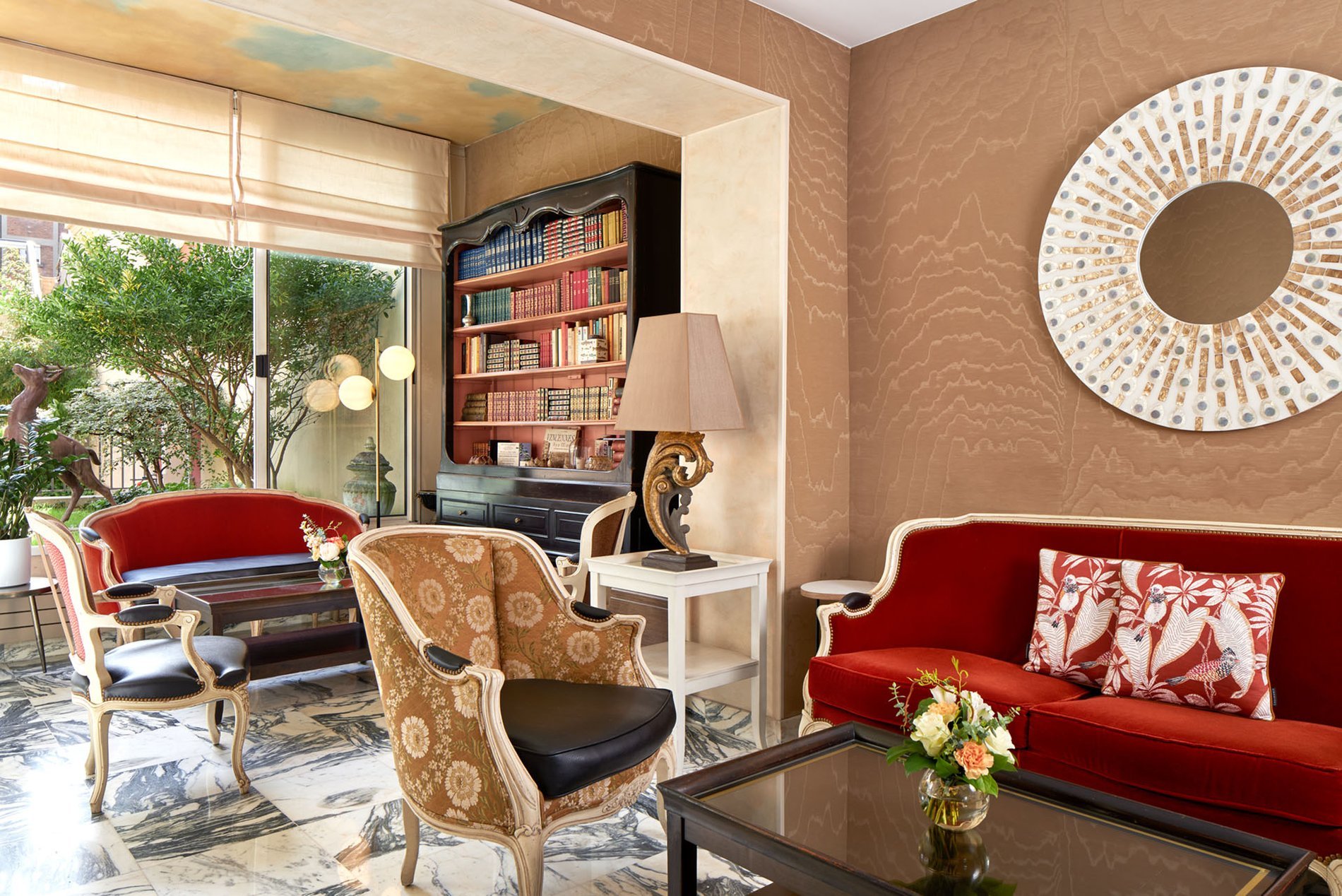 Elegant lounge at the Best Western Saint-Louis Hotel featuring comfortable armchairs, a red sofa, and a bookcase.