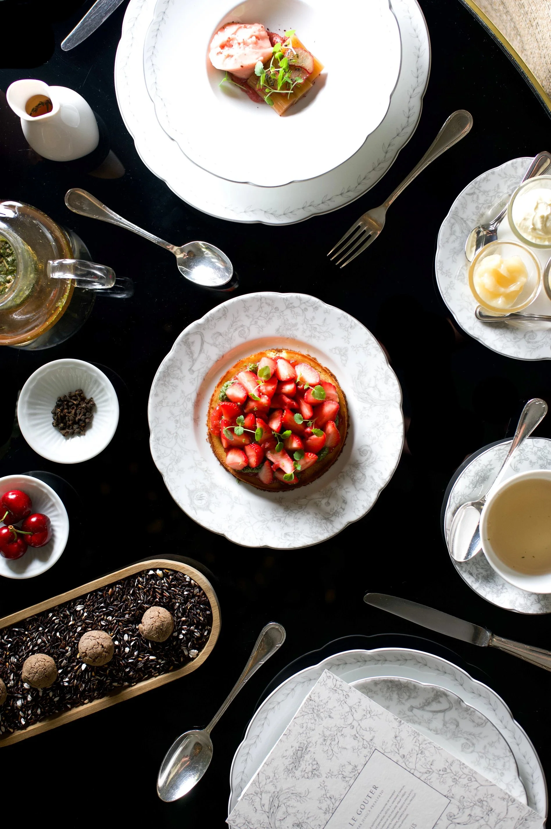 Table dressée pour un goûter à la française à l’hôtel San Régis, avec tarte aux fraises, thé et douceurs sucrées.