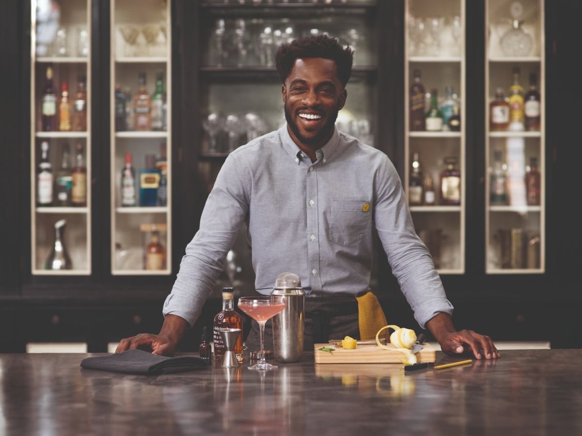 Smiling bartender preparing drinks at the stylish bar of the restaurant at VOCO Paris Montparnasse.