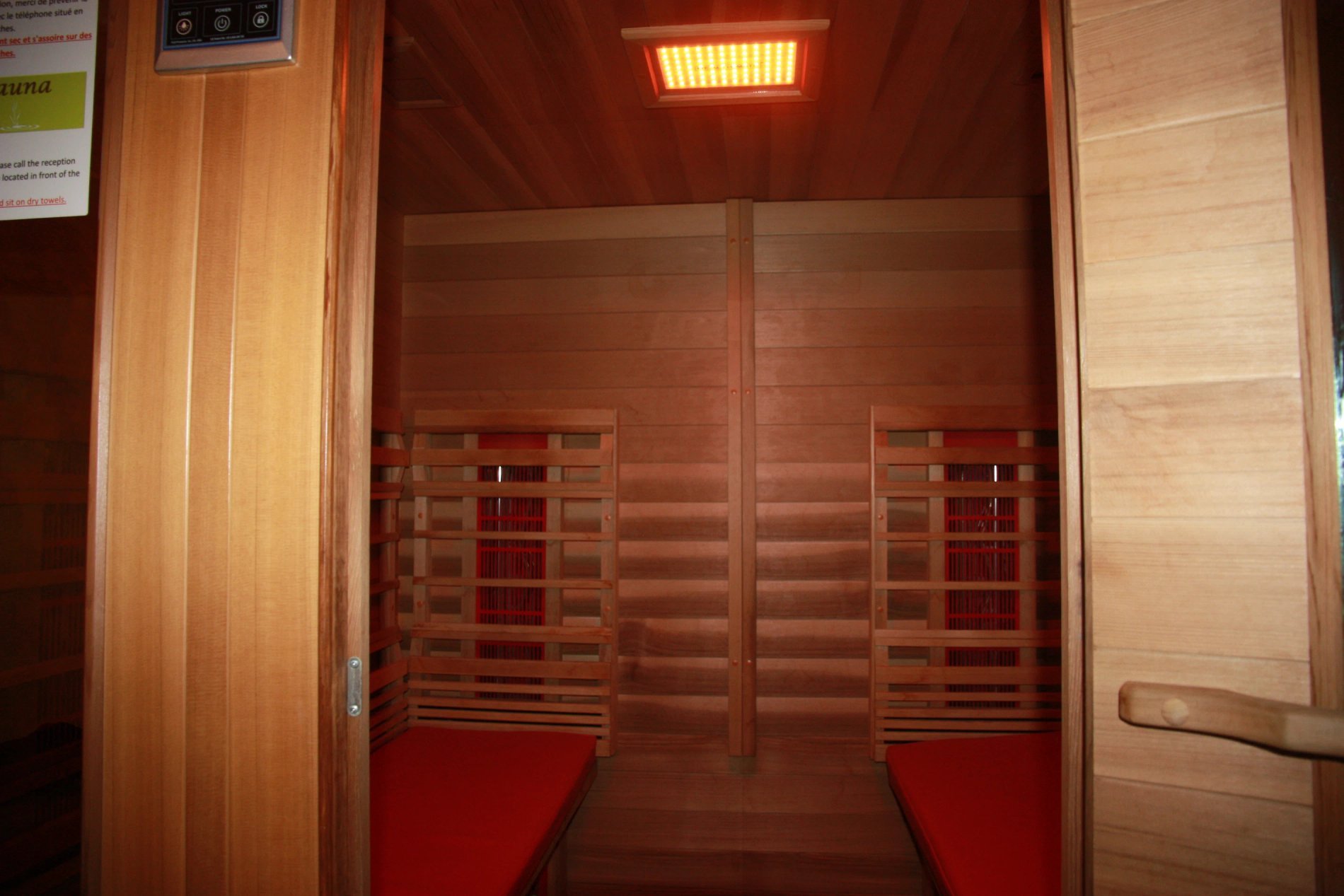 Intérieur d’un sauna infrarouge en bois à double banquette, situé dans Villa Corrèze Aventure.