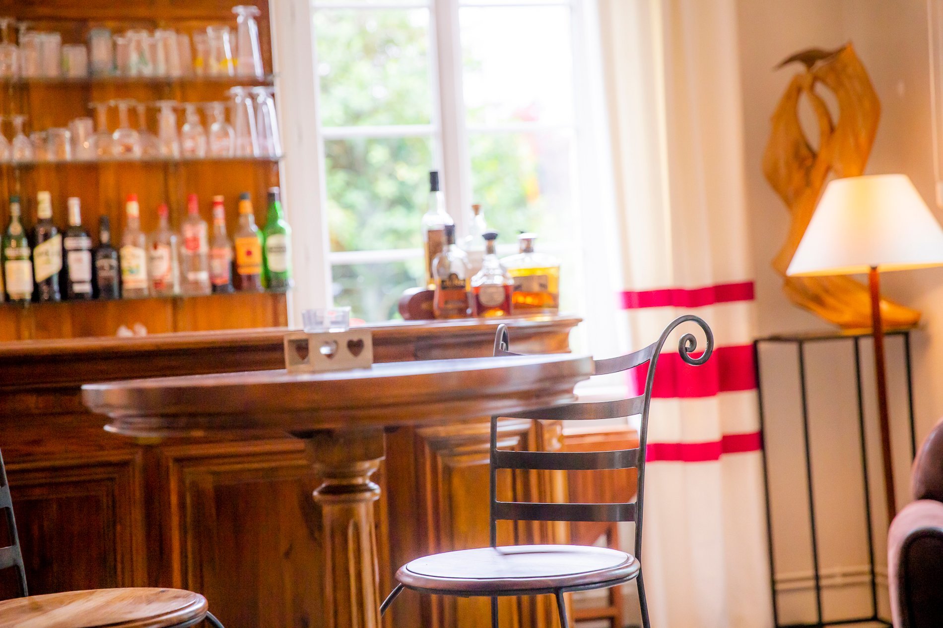 Comptoir de bar de l'Hôtel La Ramade éclairé, symbolisant l'atmosphère accueillante et raffinée en soirée.