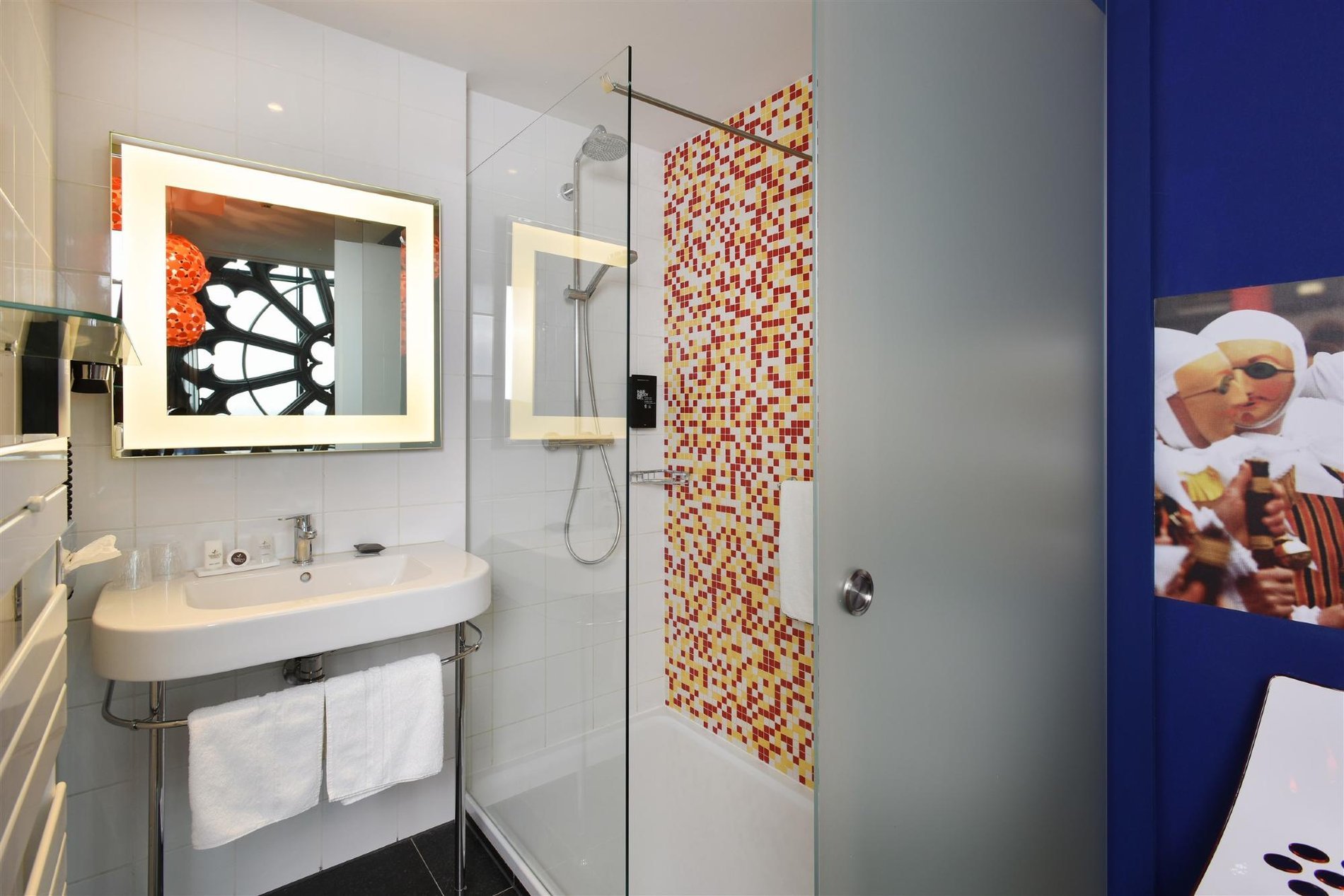 Designer-Badezimmer mit hinterleuchtetem Spiegel und geräumiger Dusche.