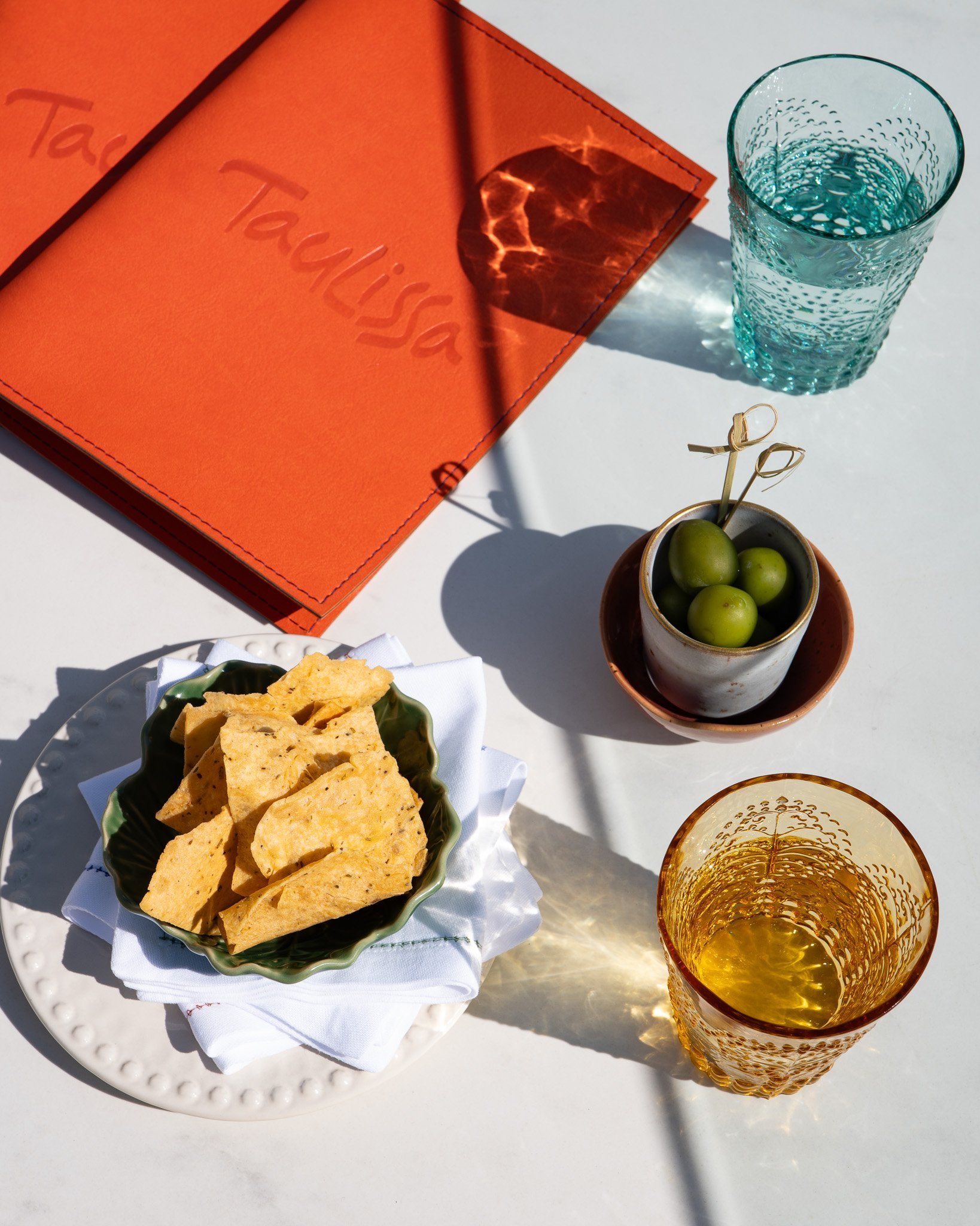 Ambiance apéro : verre, olives, chips, carte Taulissa.