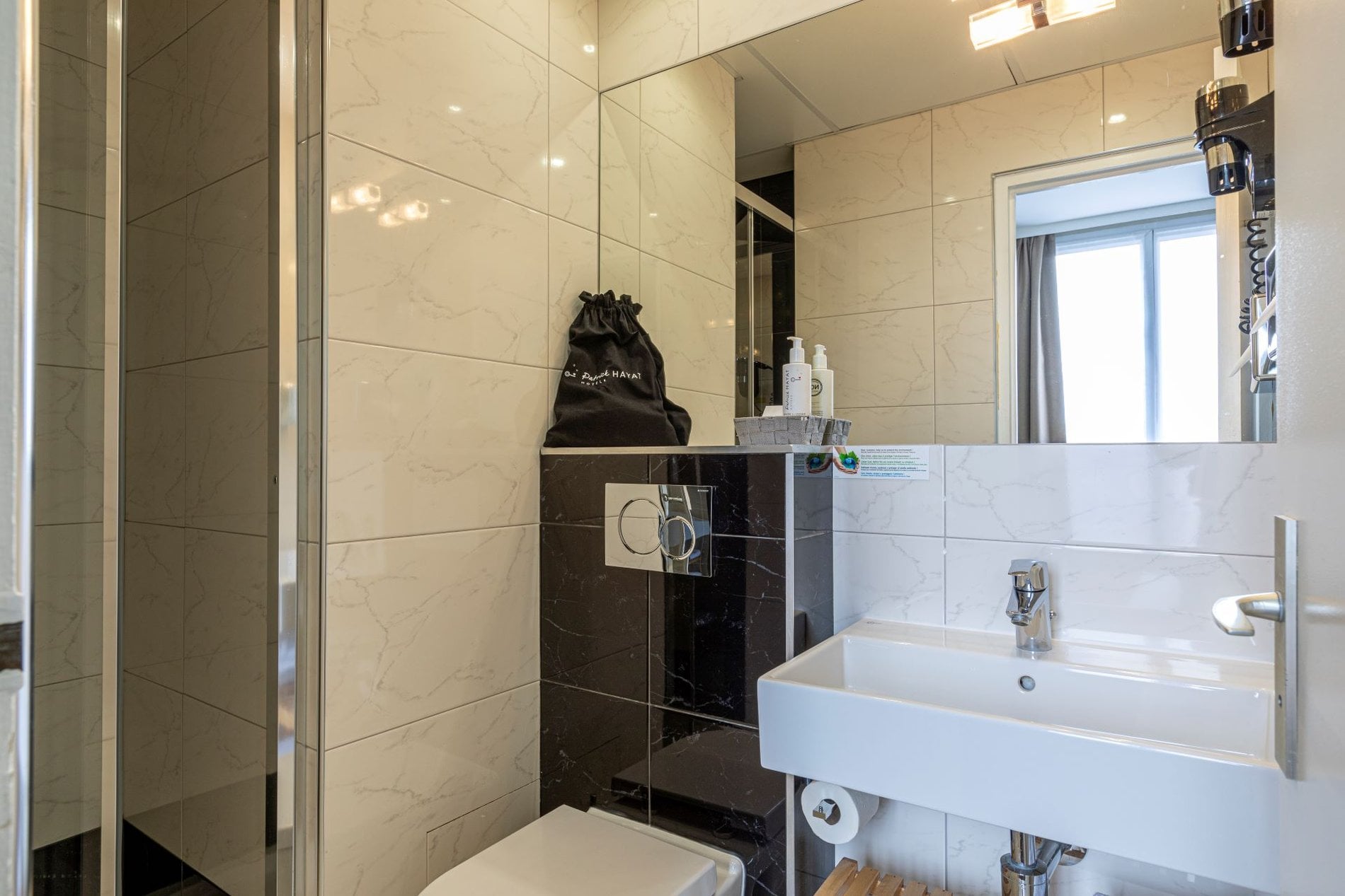 Salle de bain privative de l’Hôtel Olympic à Boulogne-Billancourt avec douche, lavabo moderne et équipements de confort.