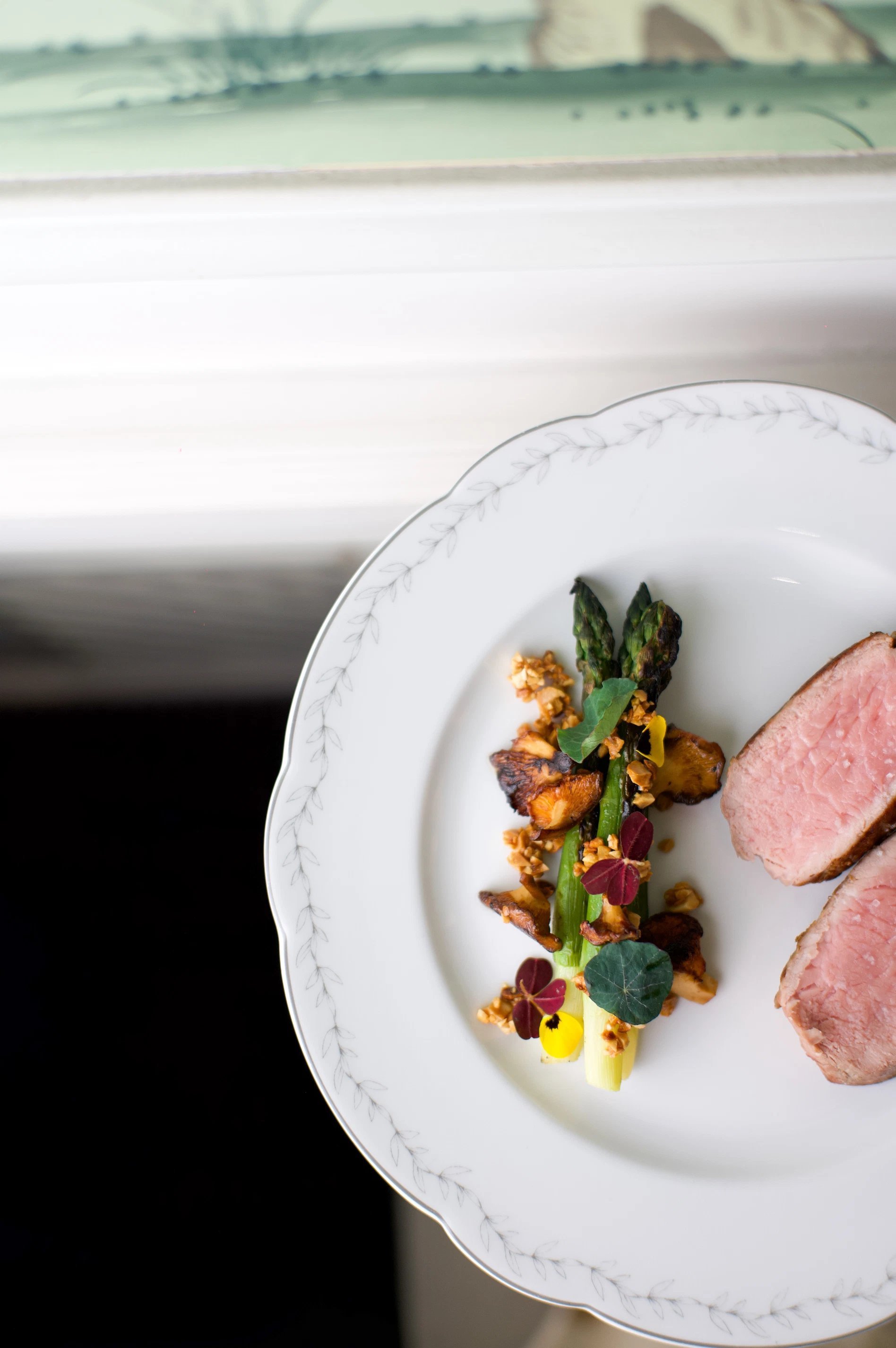 Plat gastronomique de viande rosée et légumes, servi à l’Hôtel San Régis sur une assiette blanche