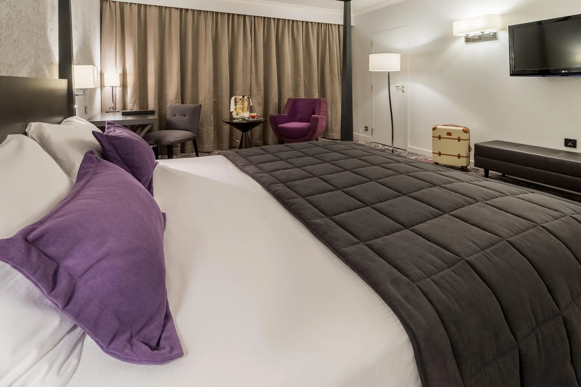 Moderne kamer met tweepersoonsbed, grijze sprei en bureauhoek bij Martin's Château du Lac.