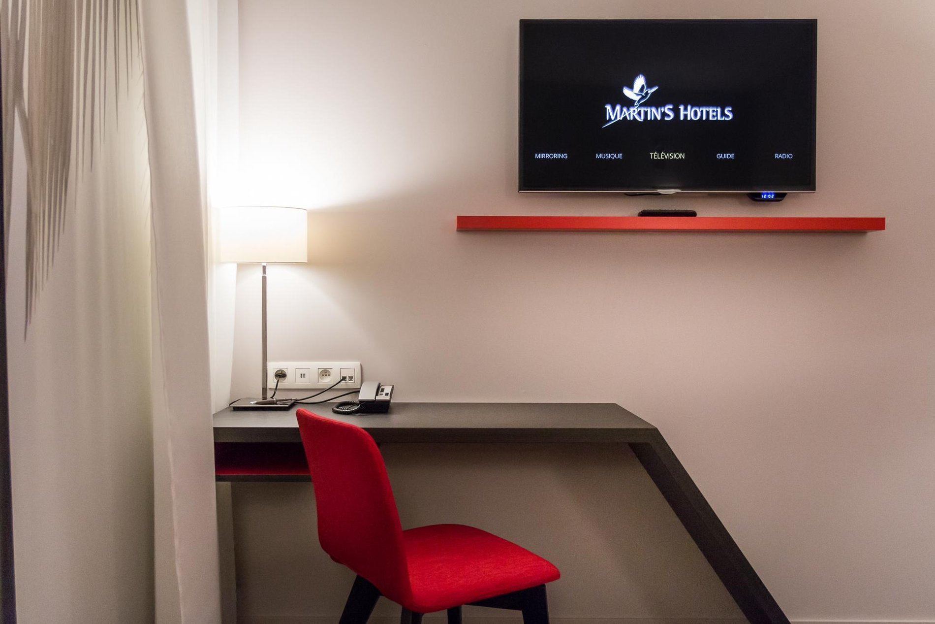 Work area in a room at Martin's Red with a wall-mounted TV and a red chair.