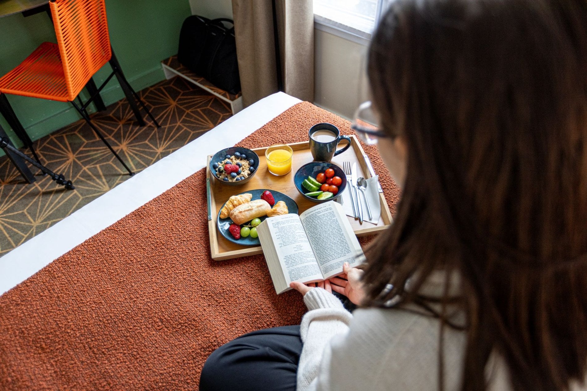 Petit-déjeuner servi en chambre à l’Hôtel Olympic à Boulogne-Billancourt avec boissons chaudes, fruits frais et moment de lecture au calme.