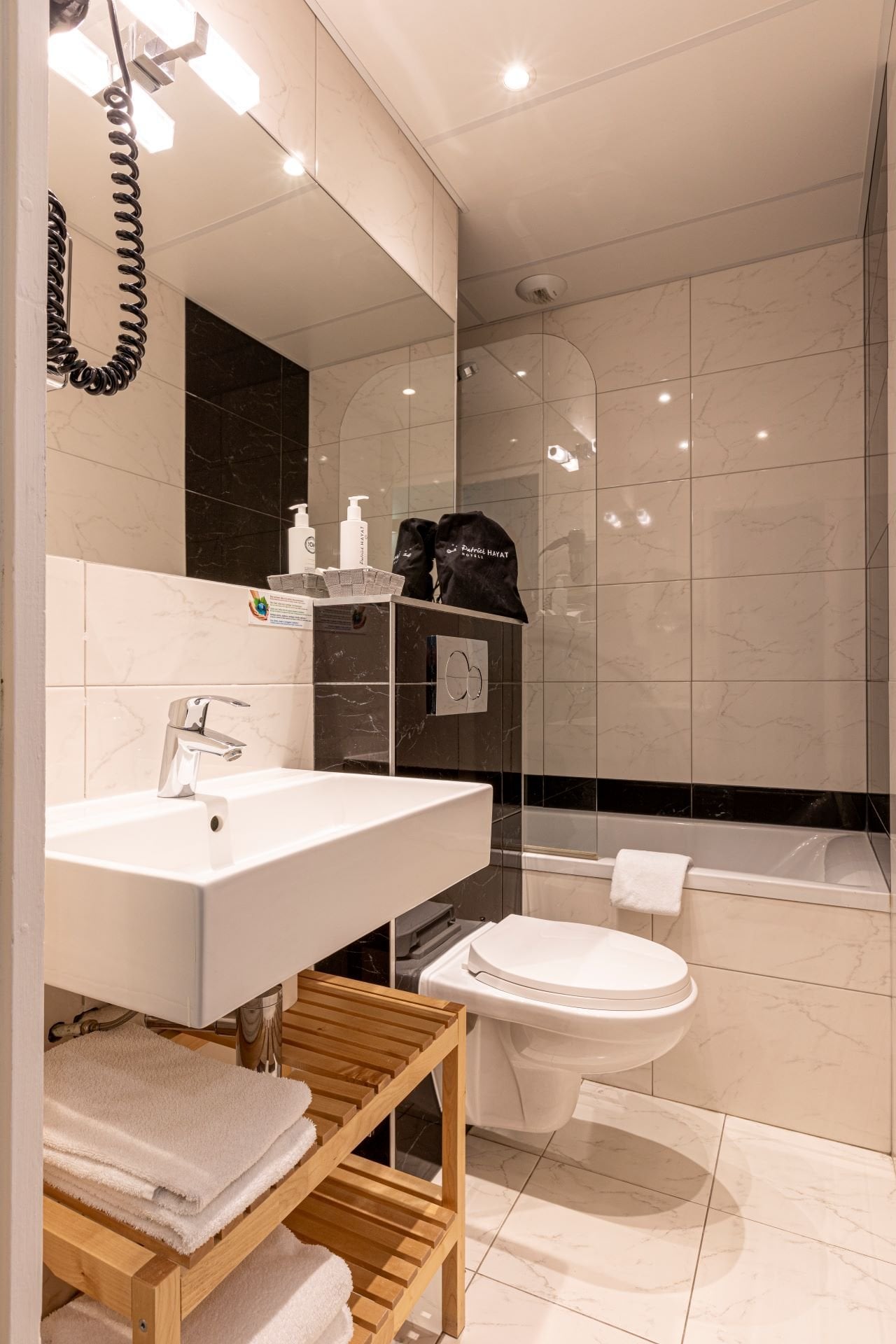 Salle de bain privative de la Chambre Classique Twin Olympic avec baignoire, lavabo moderne et produits d’accueil.