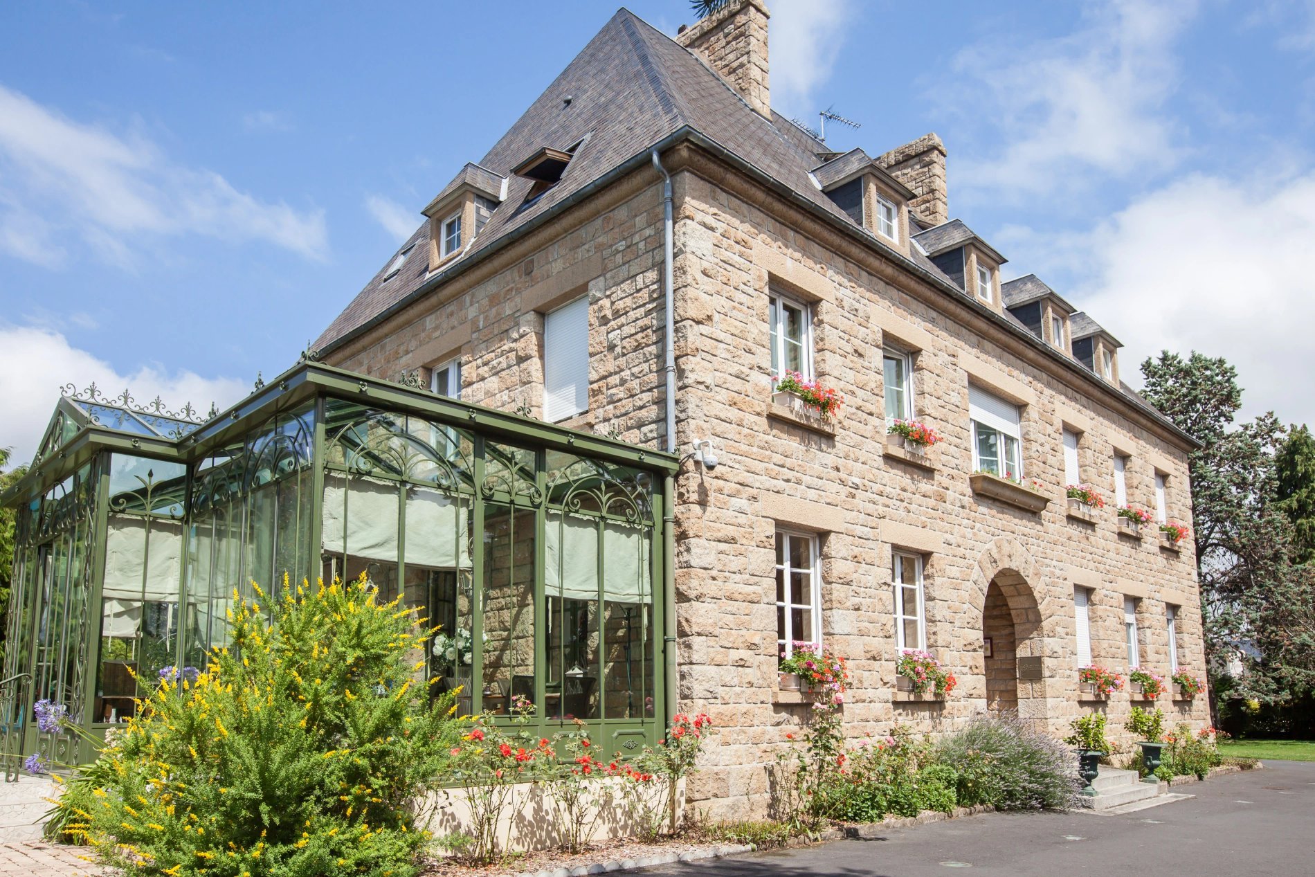 Main facade of Hotel La Ramade with conservatory and landscaping, symbolizing architecture and gardens.