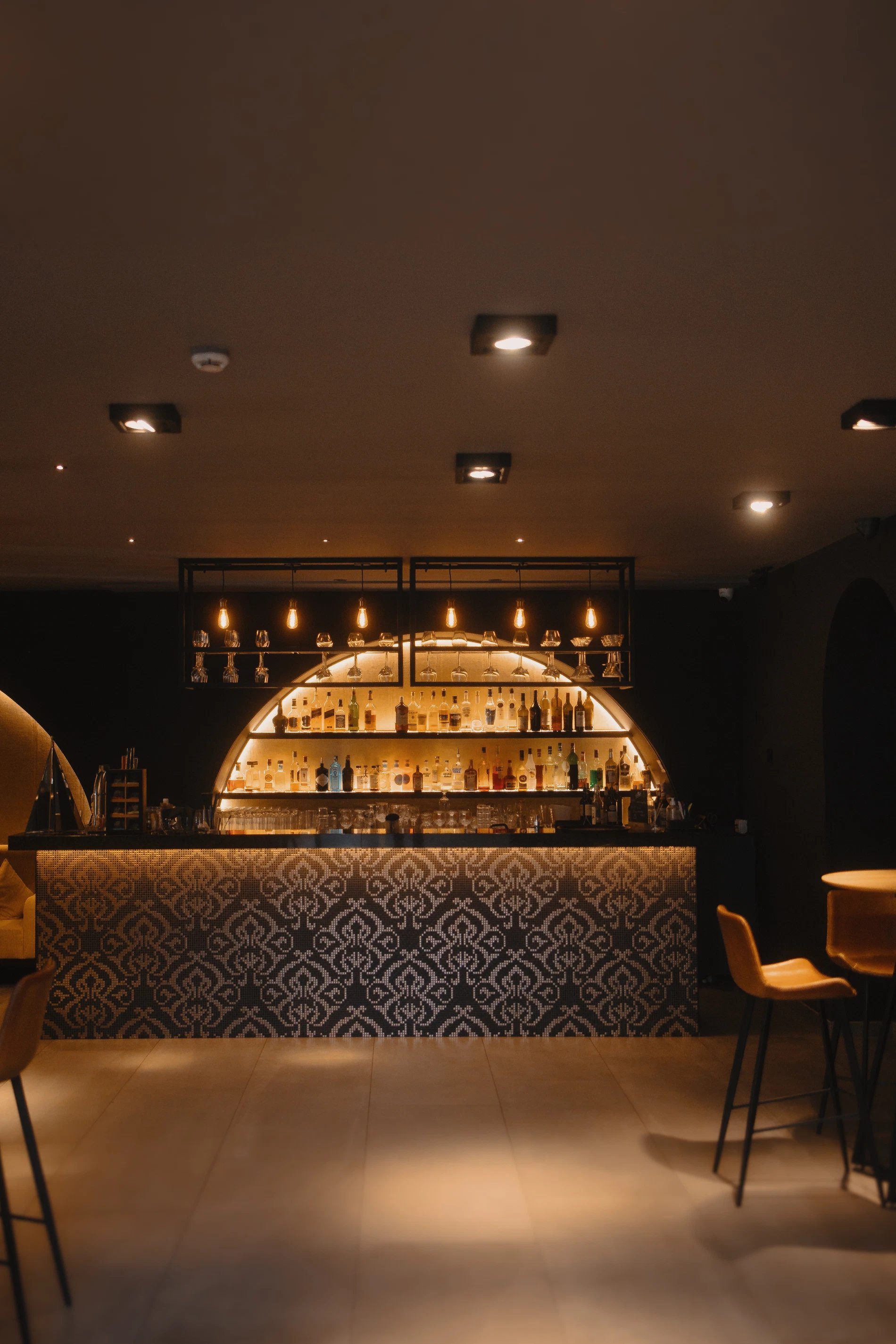 Elegant bar with dim lighting and illuminated drink display.