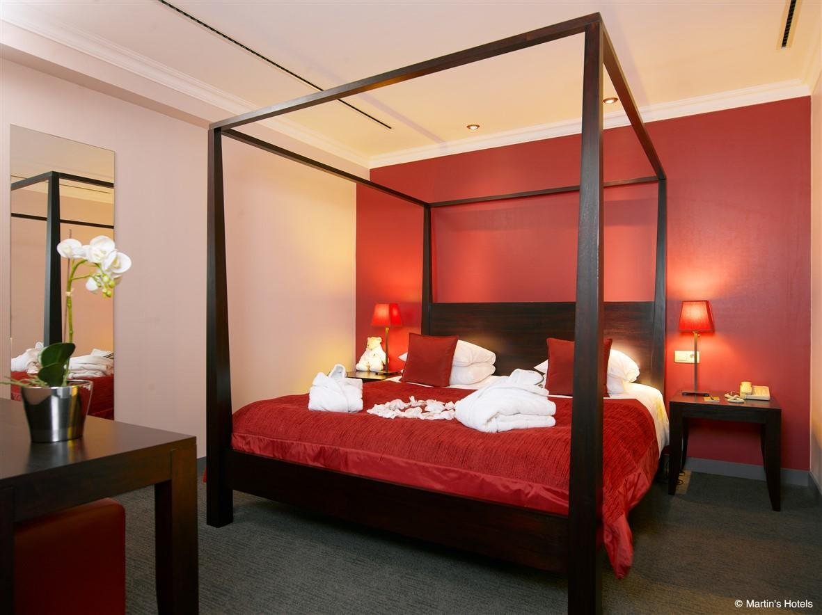 Elegant room with a canopy bed and warm red decor