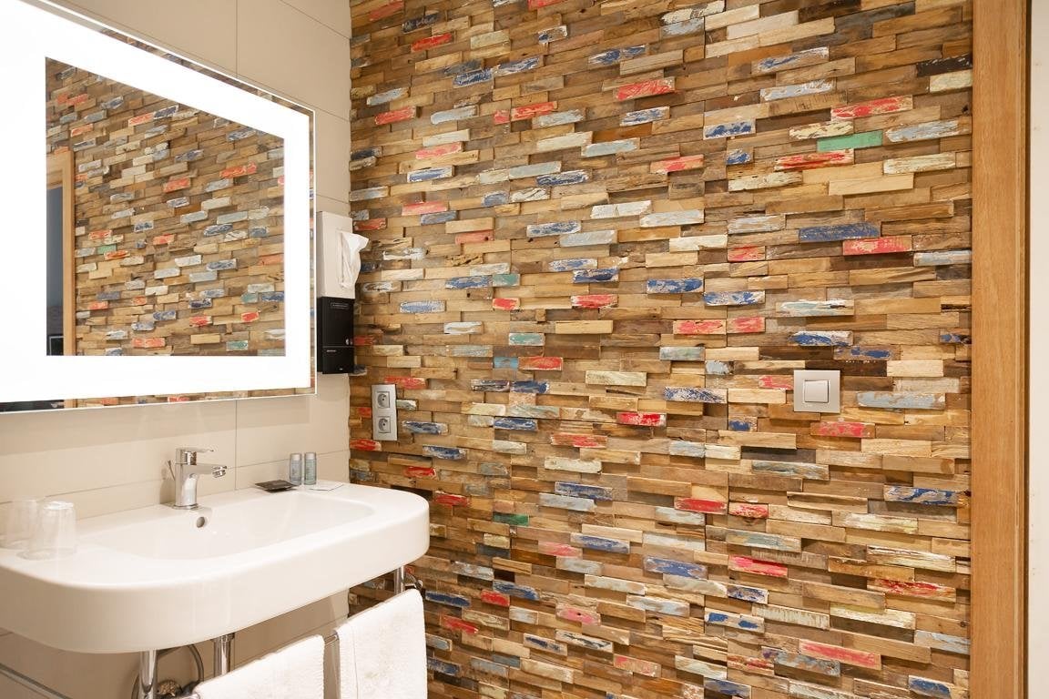 Badezimmer des gemütlichen Zimmers mit Steinwand und Spiegel.