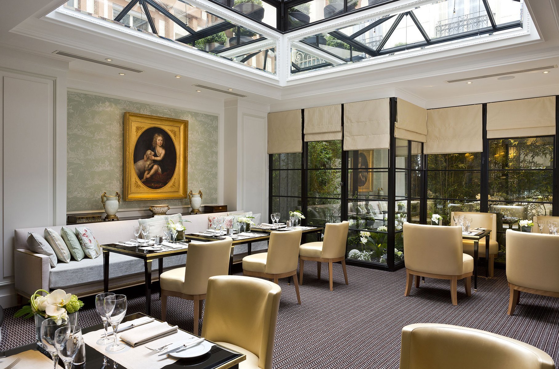 Verrière lumineuse du restaurant Les Confidences à l’Hôtel San Régis à Paris, un cadre élégant et végétalisé pour un repas romantique.