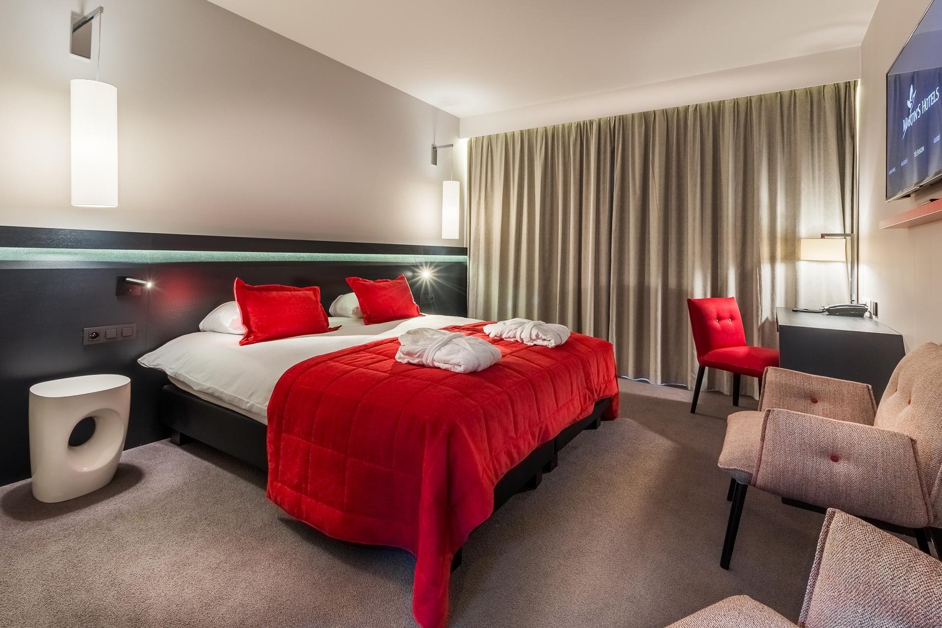 Geräumiges Familienzimmer mit Sofa und roten Vorhängen