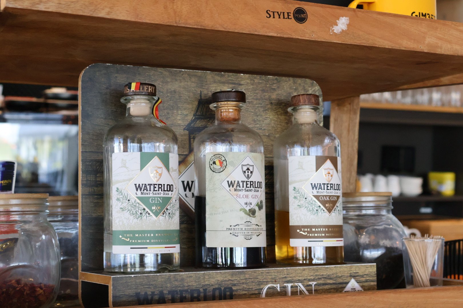 Moderne bar met planken vol flessen en schermen waarop sportevenementen worden getoond.