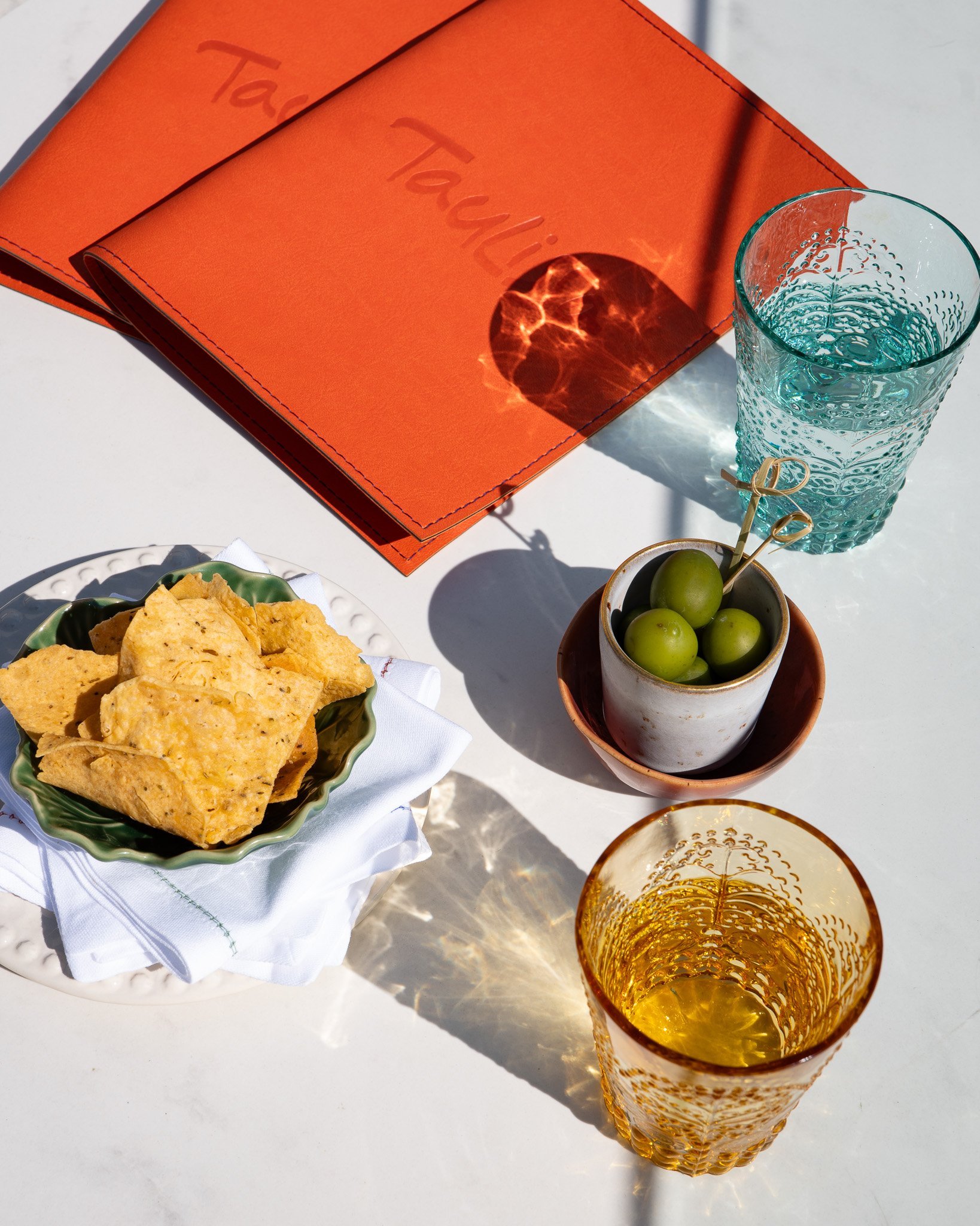 Aperitif atmosphere: glass, olives, chips, Taulissa menu.