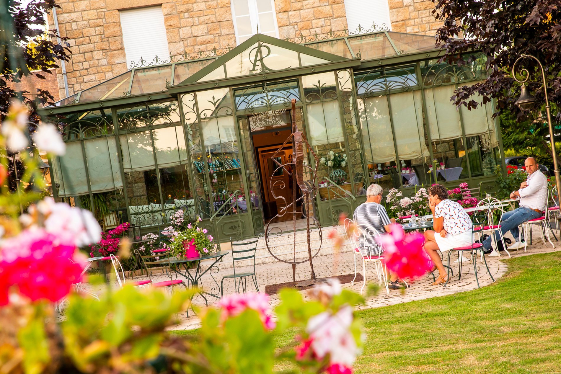 Jardin verdoyant de l'Hôtel La Ramade avec serre, symbolisant un cadre paisible pour se détendre.
