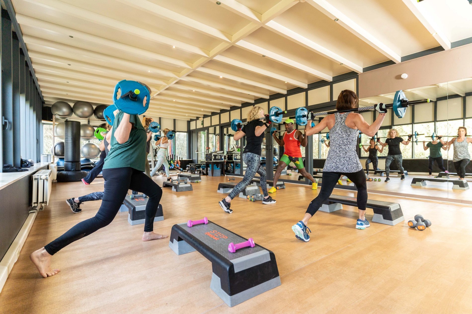 Gruppen-Fitnesskurs in einem geräumigen und hellen Raum.