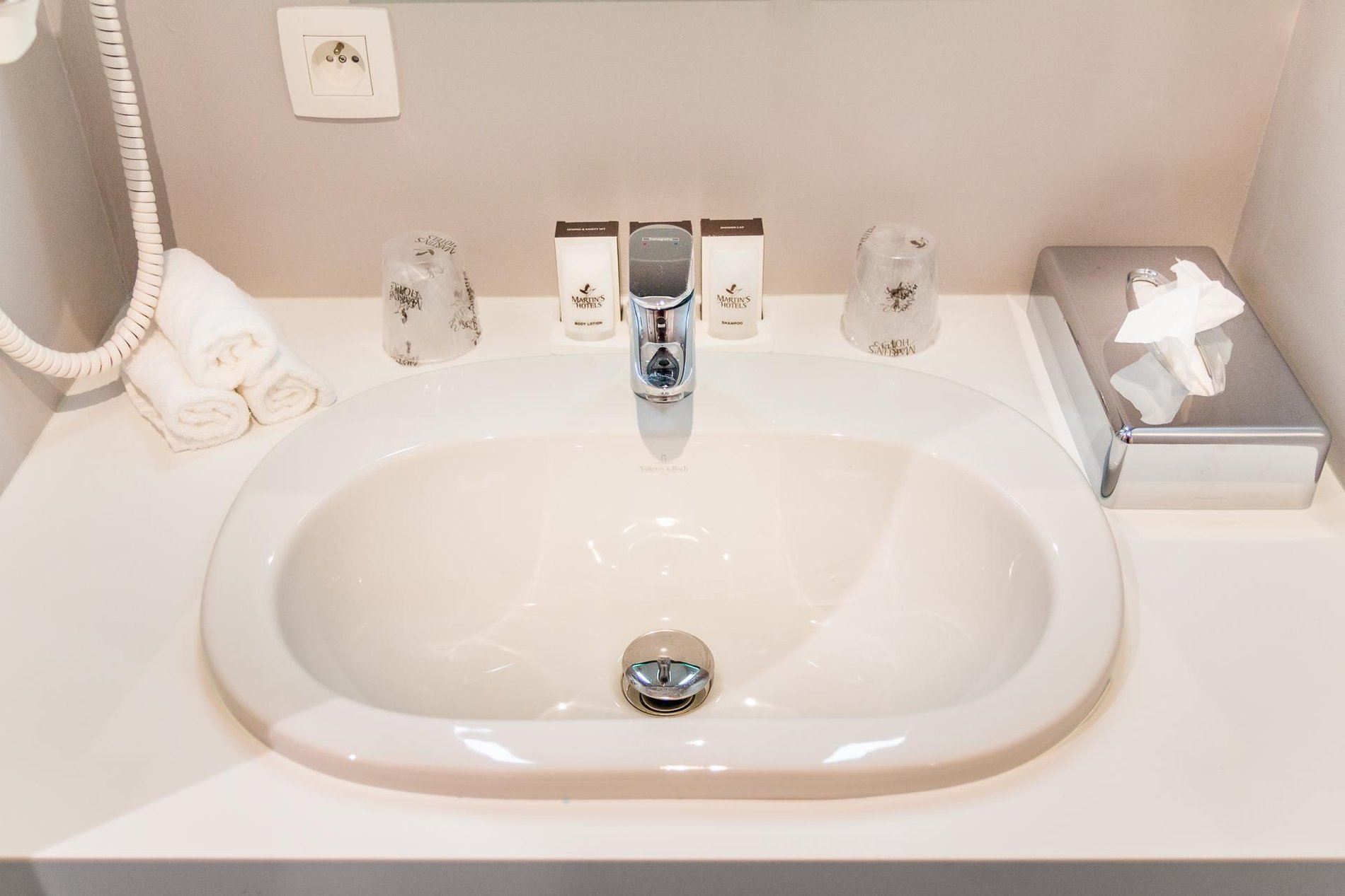 Modern sink in a bathroom at Martin's Red with chrome faucet and toiletries.