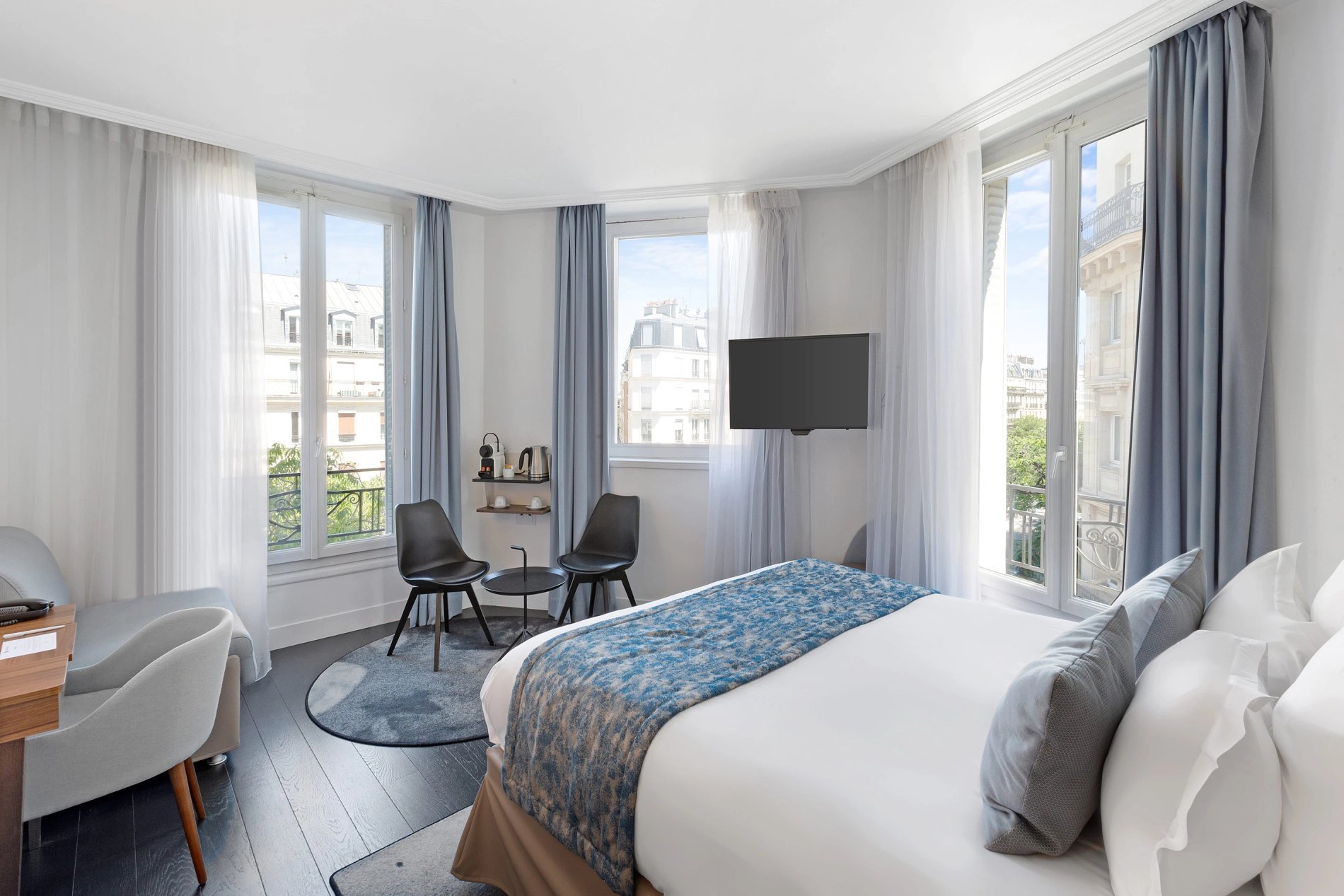 Chambre triple avec lits et fauteuil, symbolisant l'hébergement familial de BW La Demeure Paris.
