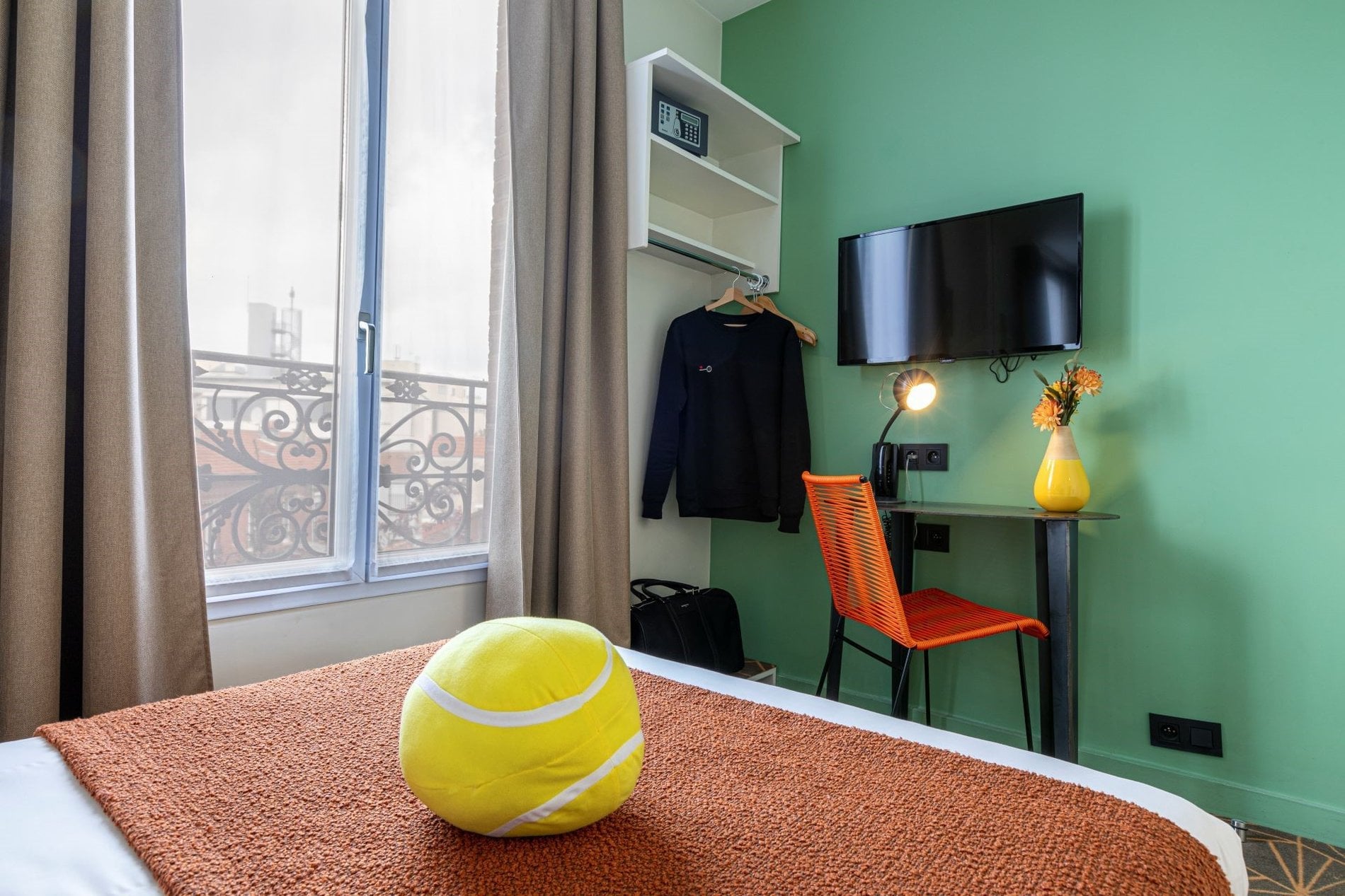 Chambre de l’Hôtel Olympic à Boulogne-Billancourt avec espace bureau, télévision murale et décoration inspirée du tennis.