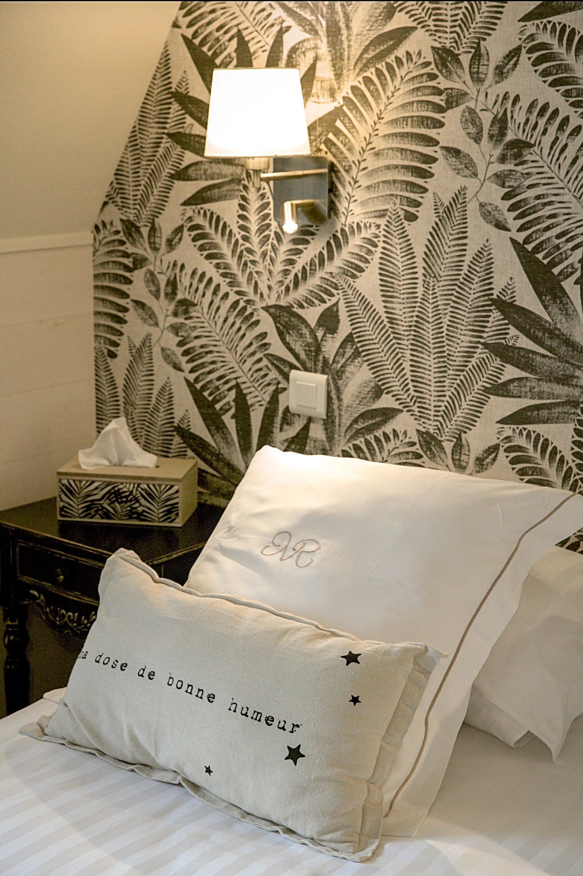 Chambre Supérieure de l'Hôtel La Ramade avec papier peint à motif de feuillage, symbolisant une décoration inspirée de la nature.