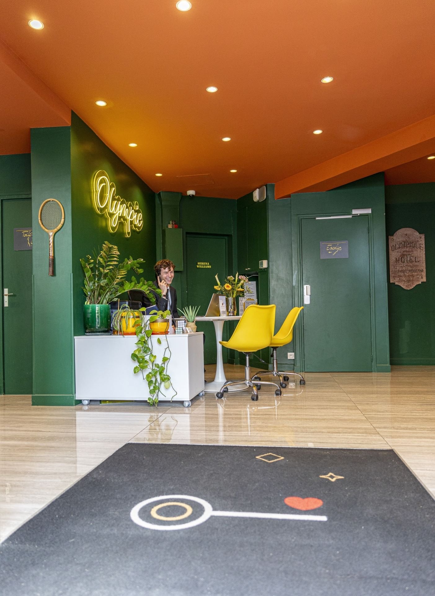 Réception de l’Hôtel Olympic à Boulogne-Billancourt avec accueil personnalisé, décoration inspirée du tennis et ambiance contemporaine.