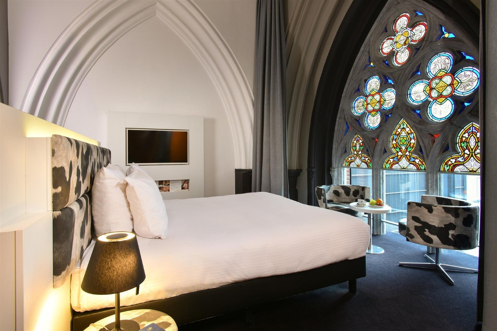 Zimmer mit Kirchengewölbe und Blick auf ein historisches Buntglasfenster.