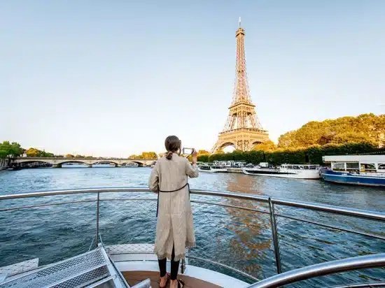 Woman taking a photo of the Eiffel Tower from a boat on the Seine River in Paris