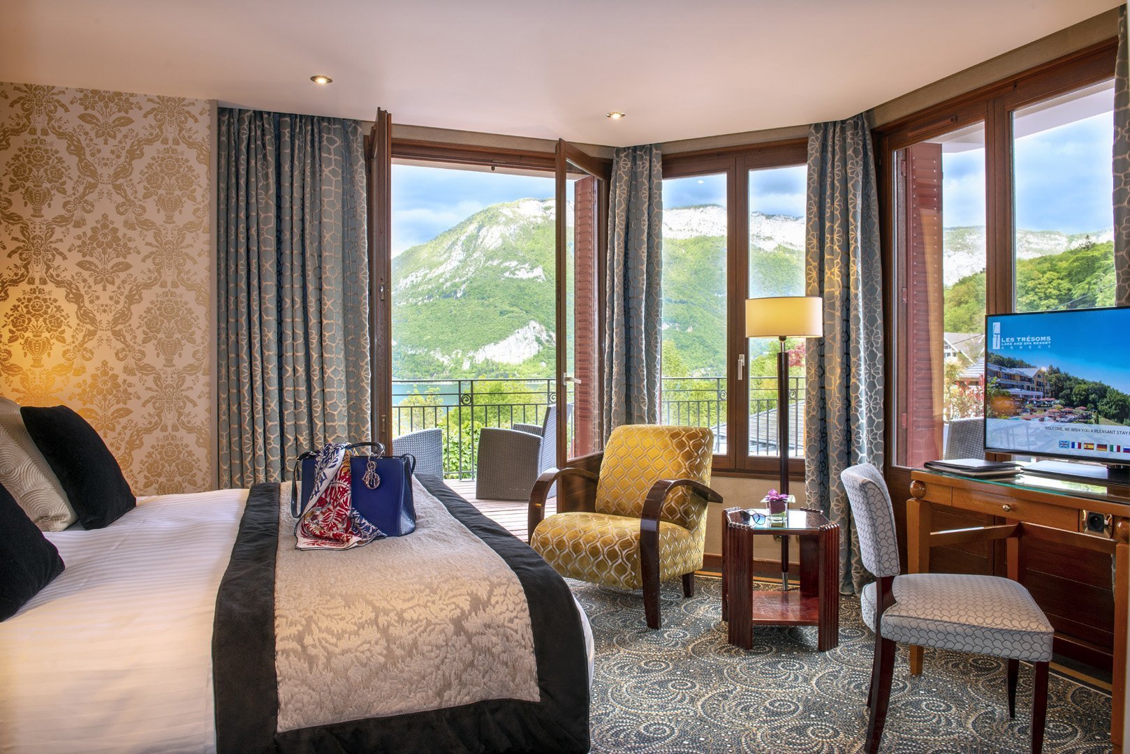 Elegance room with king-size bed, desk, bathroom and panoramic view of the mountains and Lake Annecy