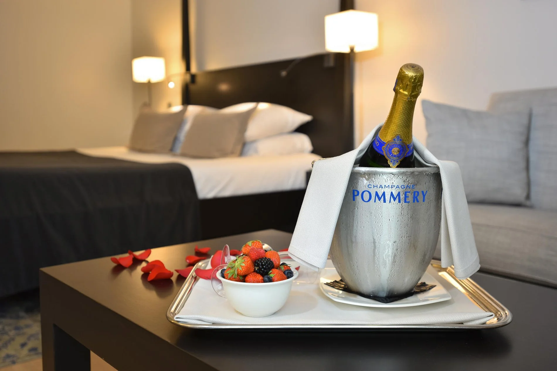 Flasche Champagner mit Erdbeeren, serviert auf einem Tablett in einem eleganten Zimmer im Martin's Château du Lac.