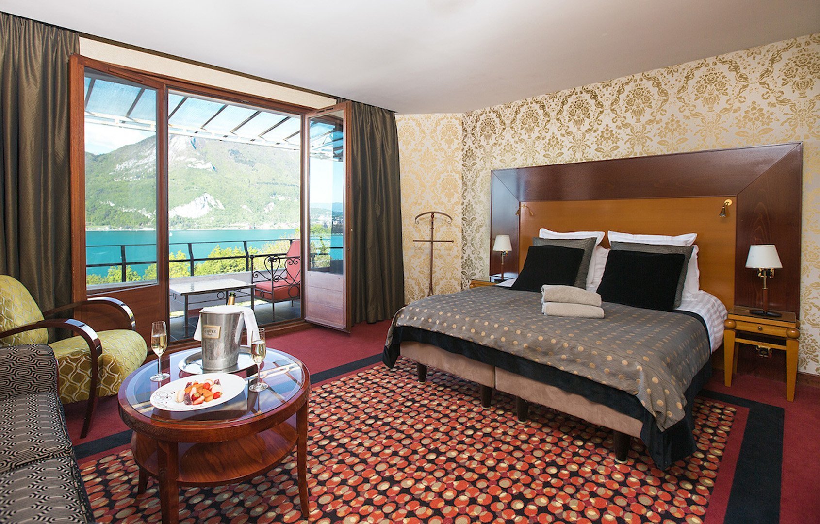 Vue panoramique exceptionnelle depuis la terrasse d'une chambre privilège de l'Hôtel Les Trésoms sur le lac d'Annecy et les montagnes.